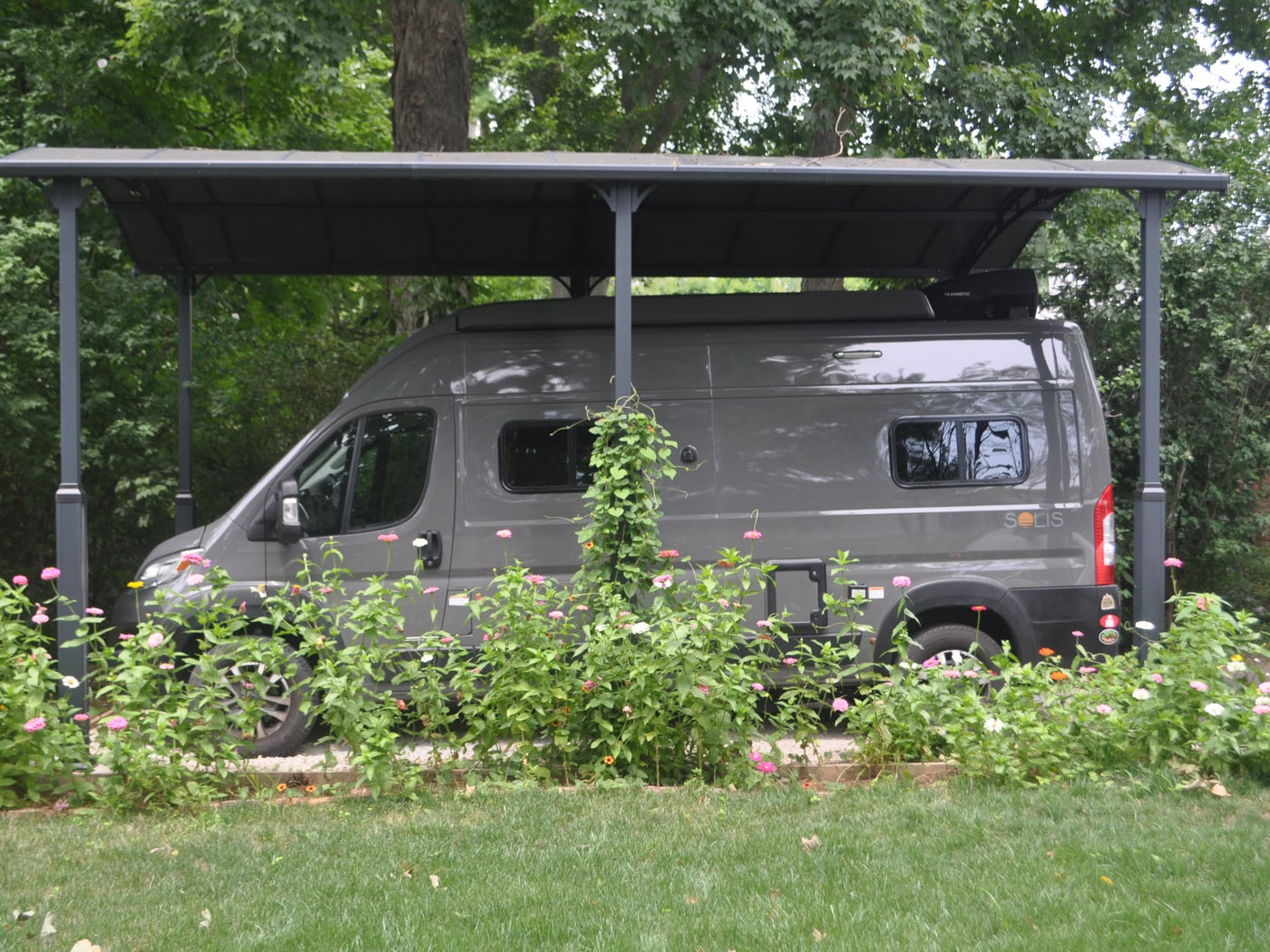 has its side door open in a tree-lined setting.|Gray Winnebago Solis camper van — photo 3