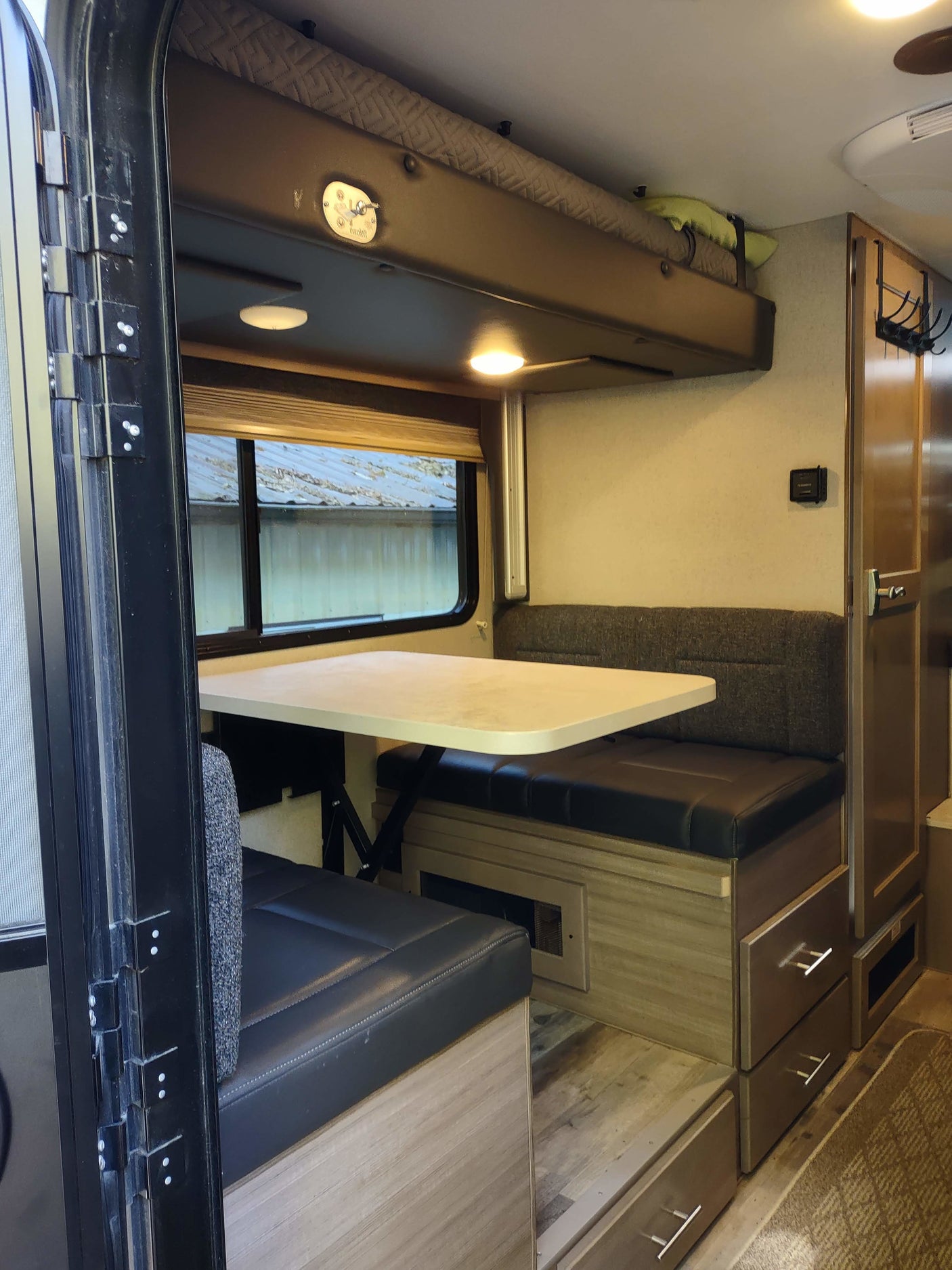 Inside this rv rental: a comfy dinette, an overhead bunk bed, and storage solutions for convenient travels.