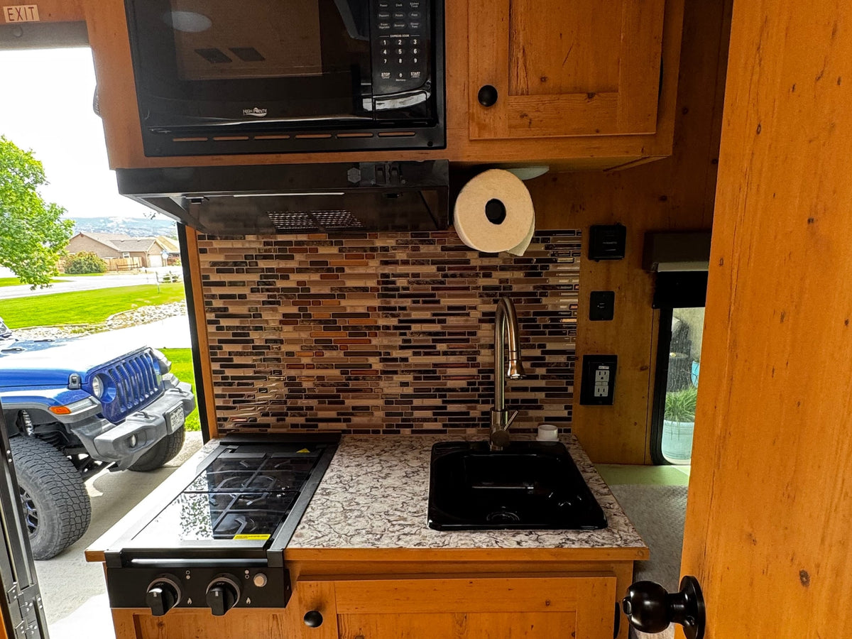 ideal for travel.|RV rental interior showcasing a compact kitchen with stovetop — photo 11
