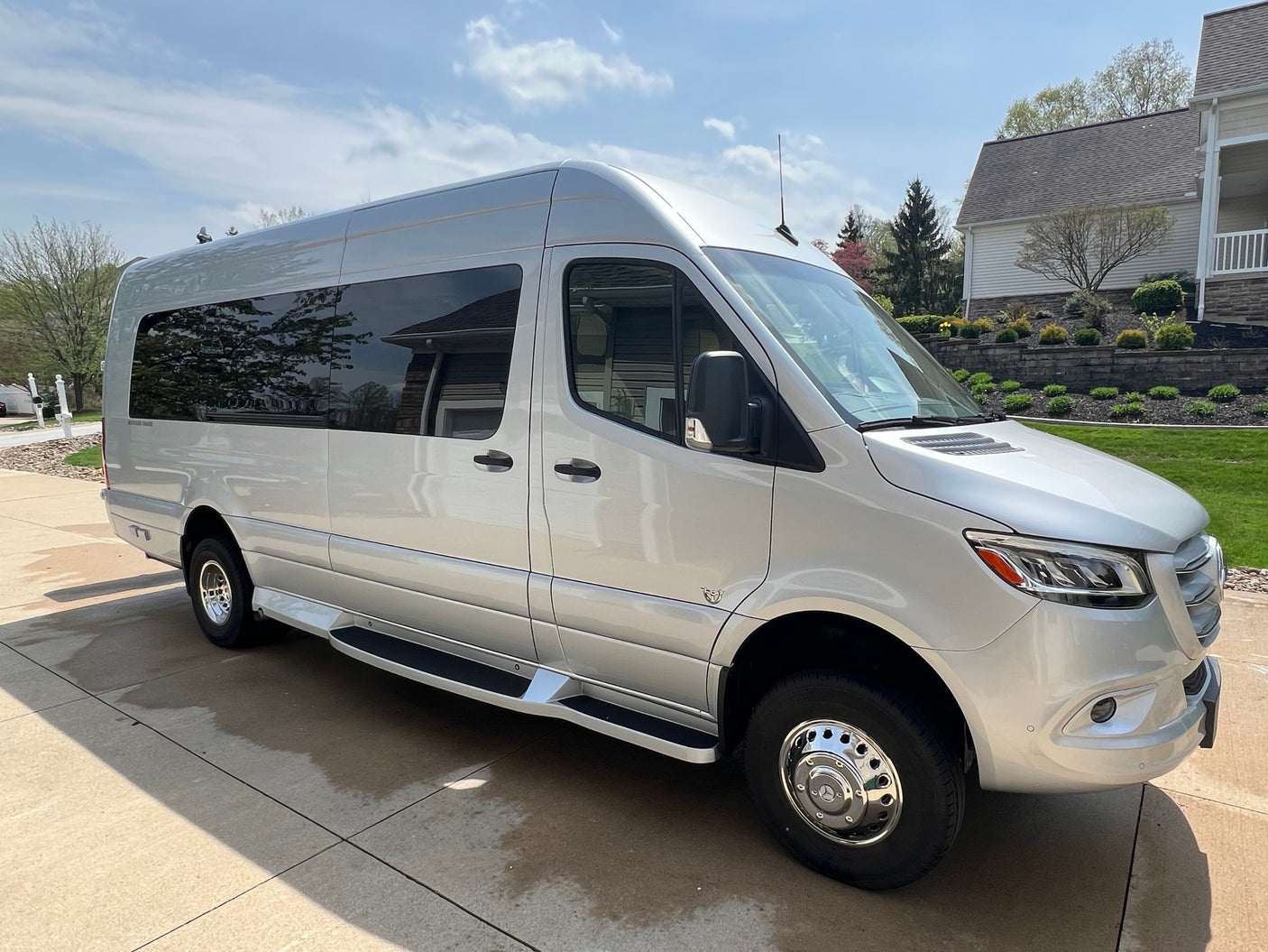 A silver Mercedes-Benz Sprinter van, ideal for rv rental adventures. This luxury conversion van is parked on a sunny driveway.