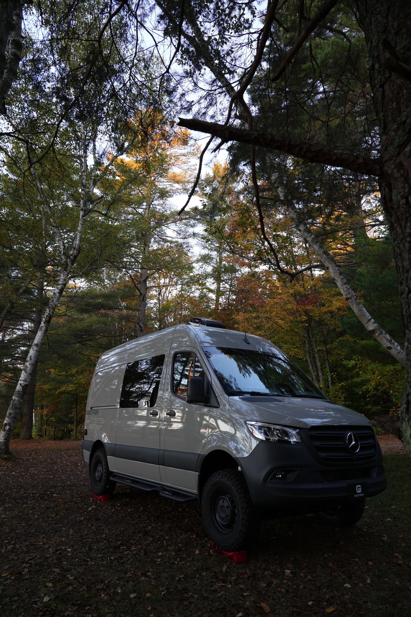 Adventure awaits with this sleek Mercedes Sprinter rv rental, nestled in a vibrant autumn forest. Perfect for nature exploration.