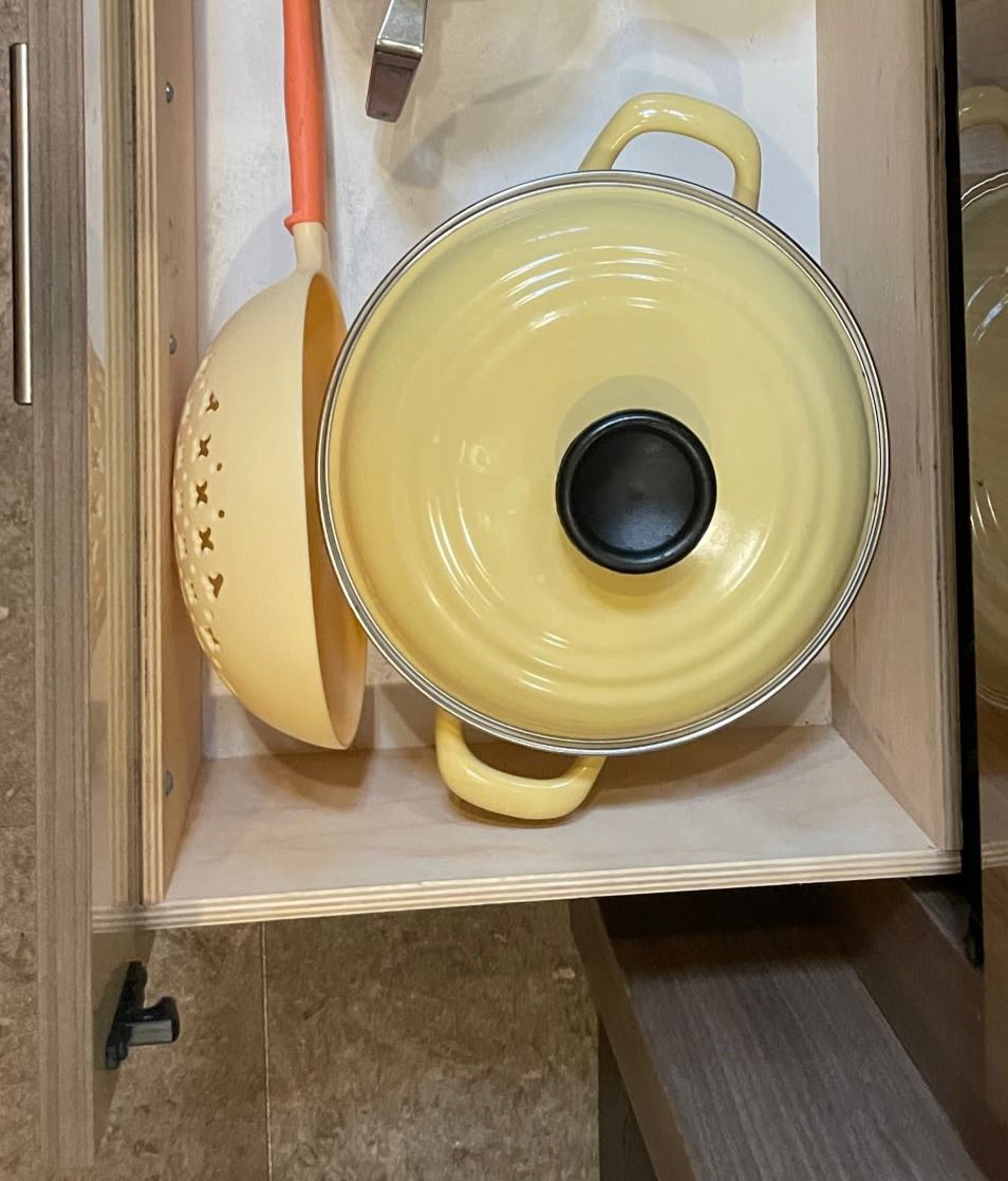 Efficient RV rental kitchen storage: yellow pot, colander in custom drawer. Perfect for compact living.