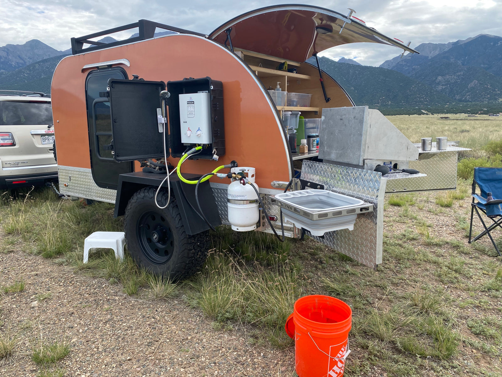 This RV rental teardrop trailer features an outdoor kitchen & shower setup for mountain camping.