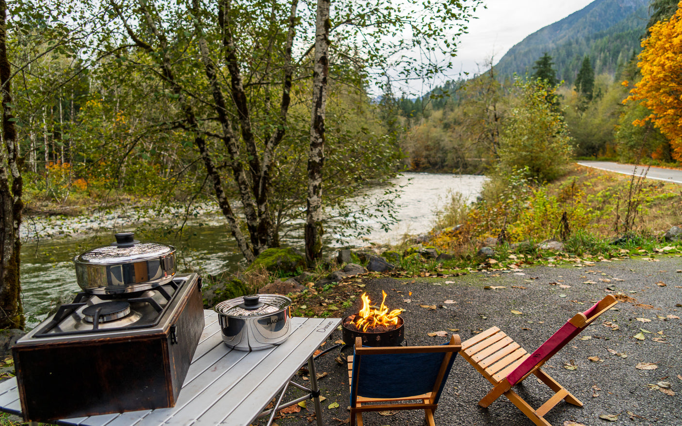 Enjoy your RV rental adventure with outdoor cooking, a warm campfire, and serene river views surrounded by vibrant fall foliage.