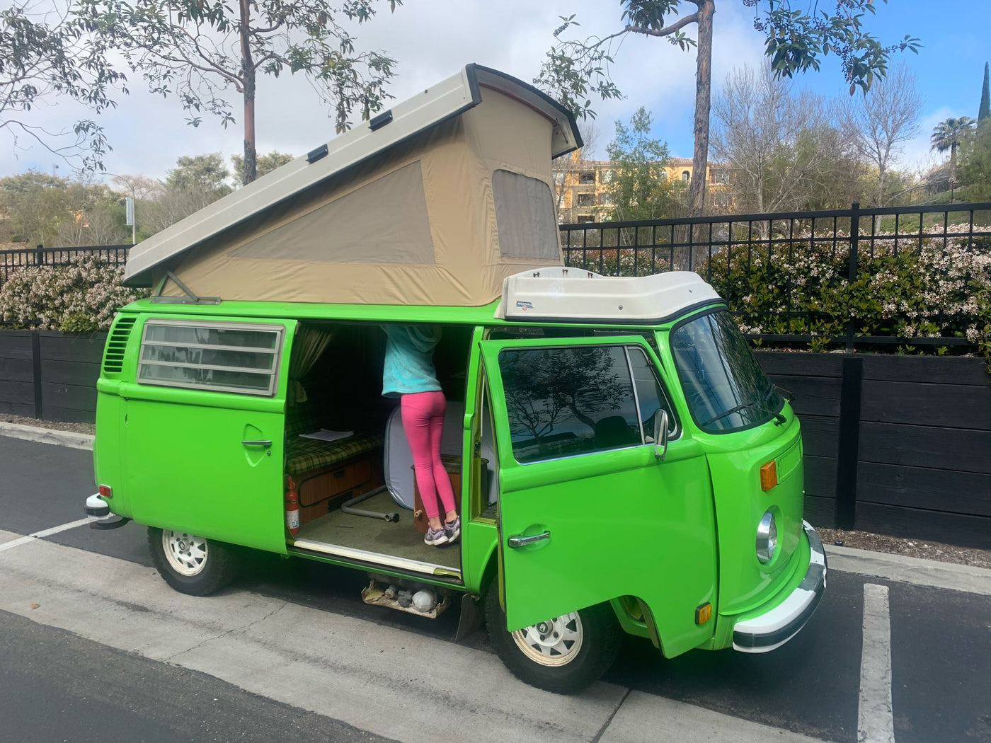 Vibrant green VW pop-top camper van with an open side door — photo 1