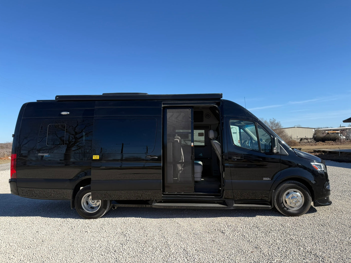 This black Mercedes-Benz Sprinter camper van, an ideal RV rental, has its side door open for a peek inside.