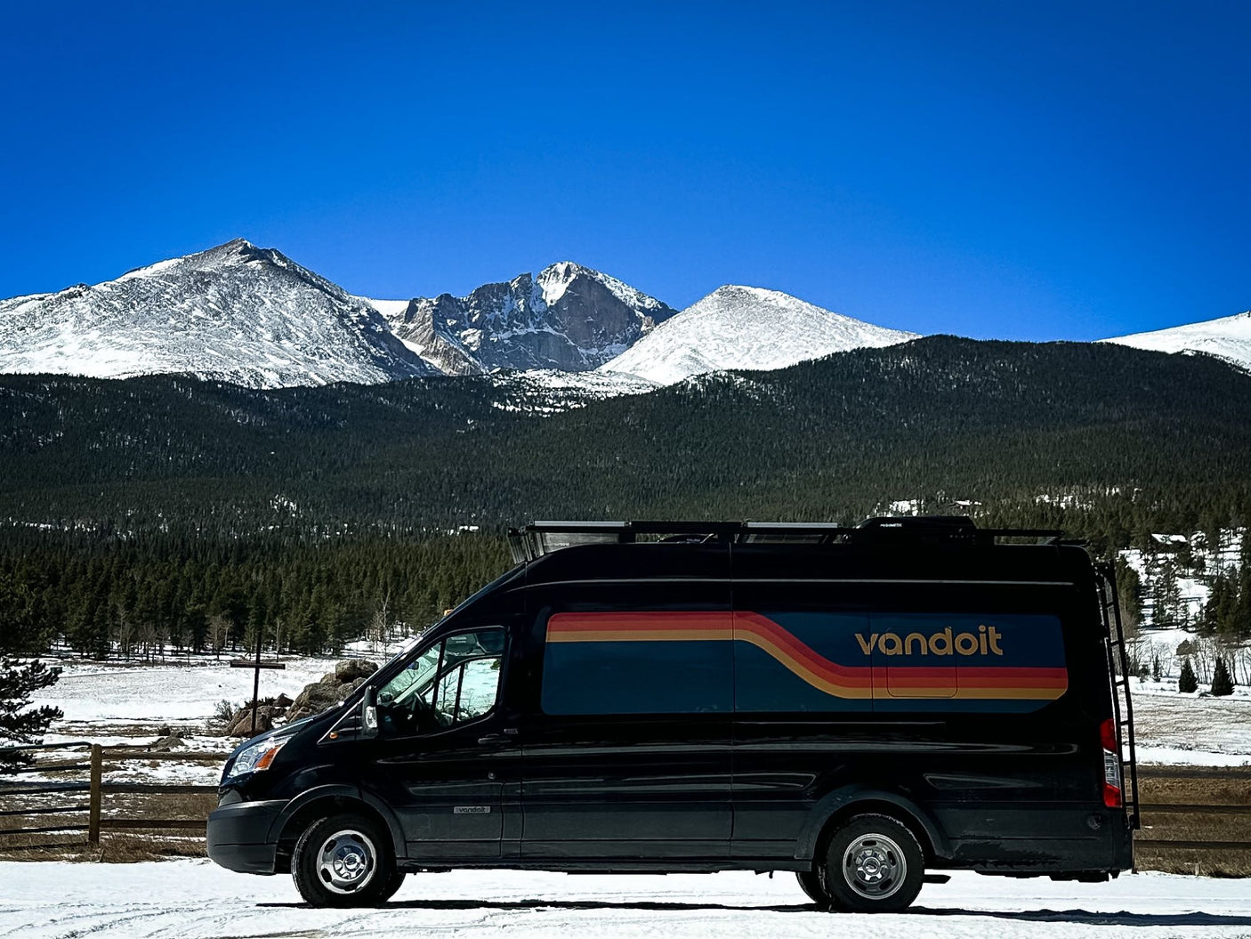 including a large arch.|An RV rental van parked among the unique Niobrara Chalk rock formations under a bright blue sky.|Black Vandoit RV rental van parked on snowy ground