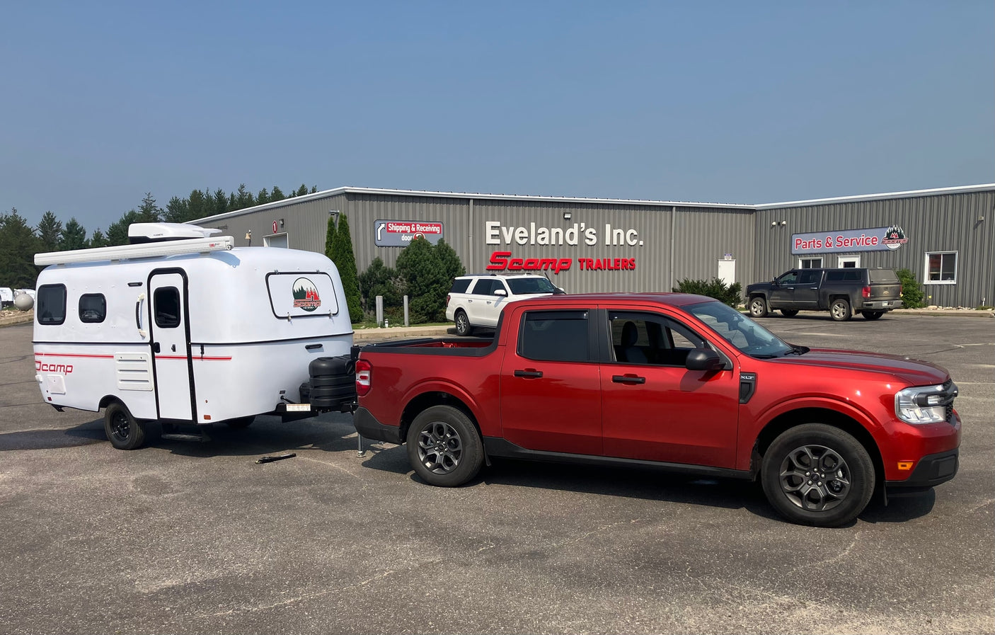 Red truck towing a white Scamp travel trailer