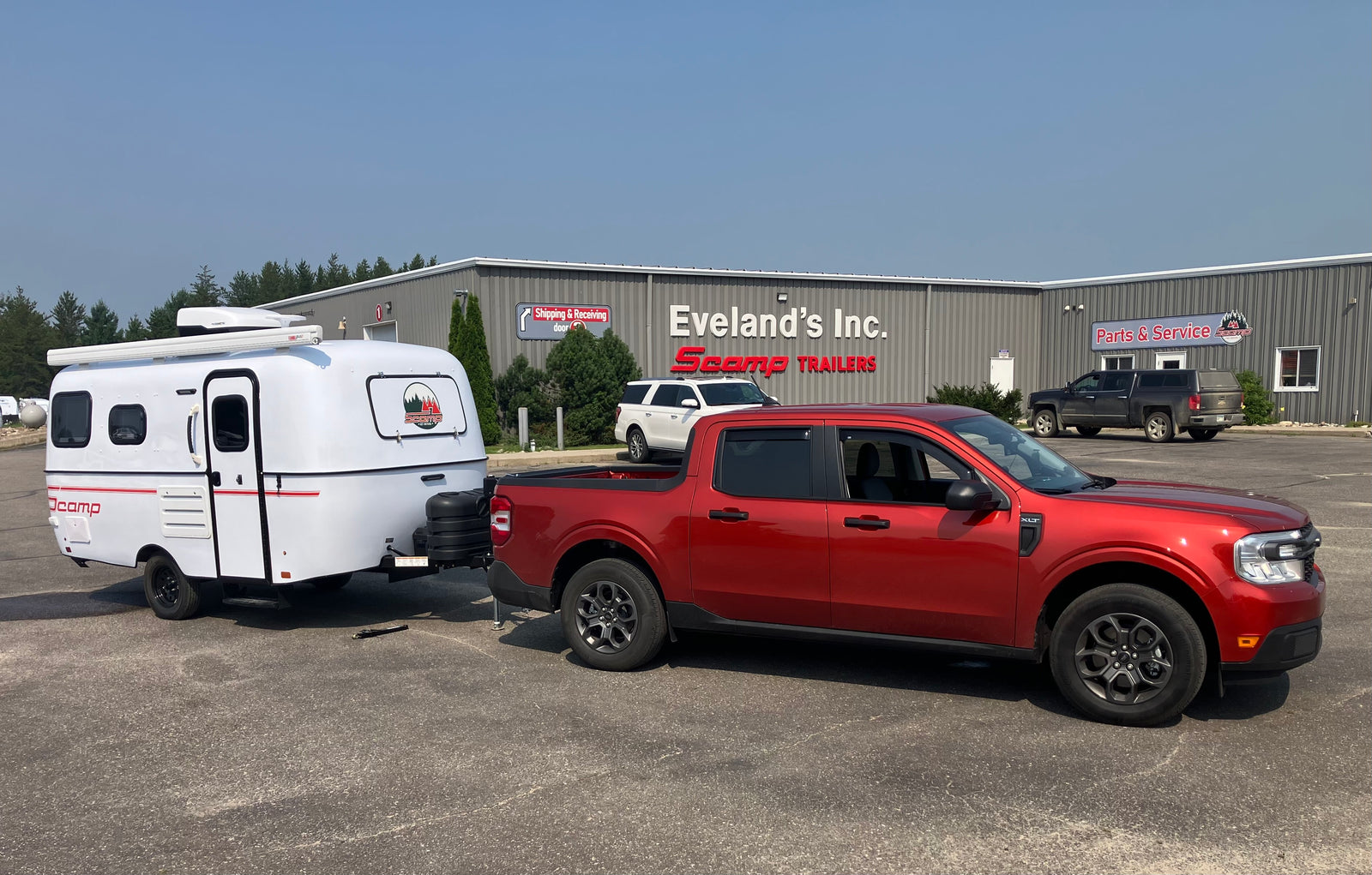 Red truck towing a white Scamp travel trailer