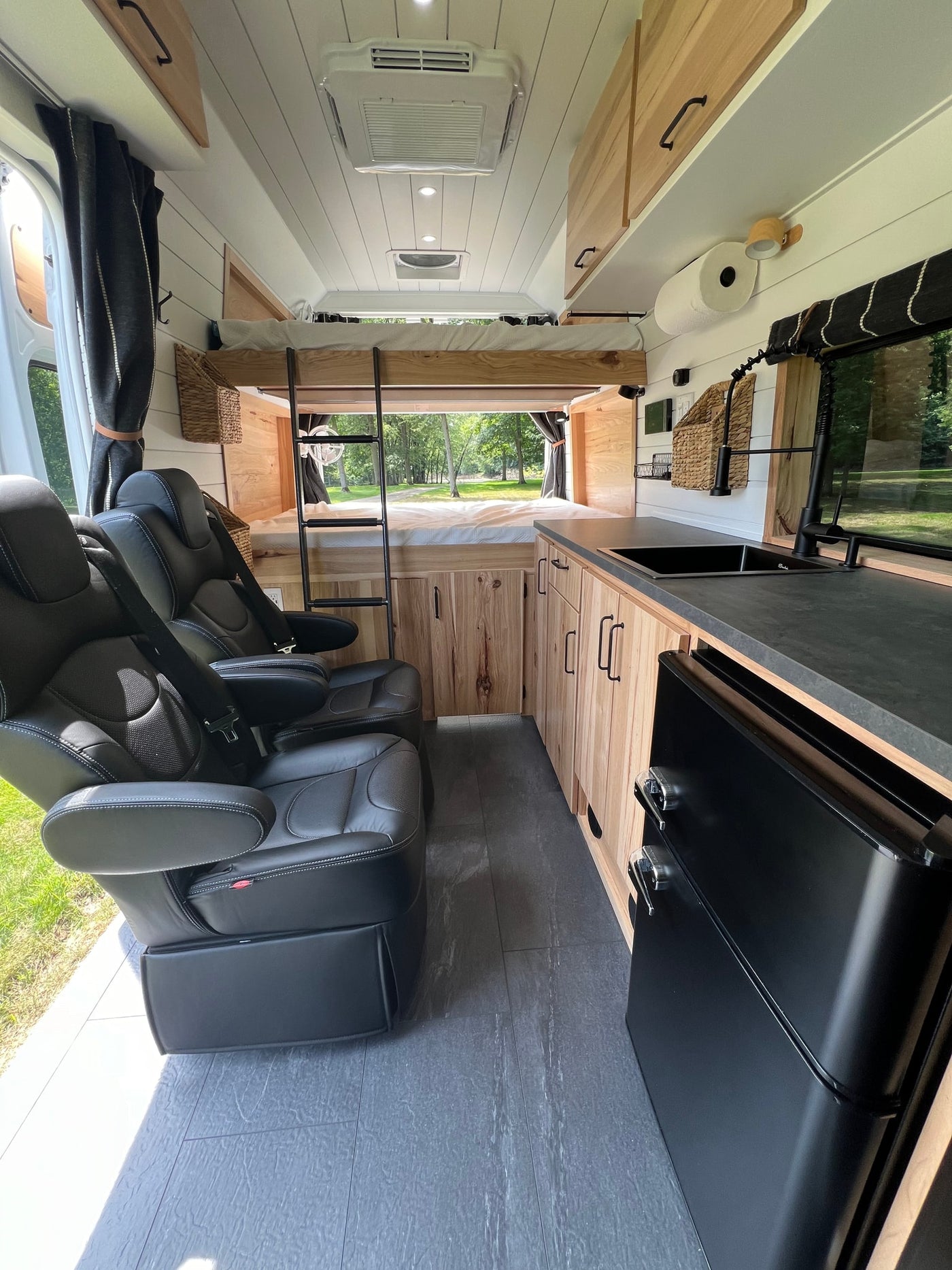 & leather captain's chairs. Brightly lit ceiling & scenic window views.|RV rental: Modern camper van interior with kitchenette — photo 3