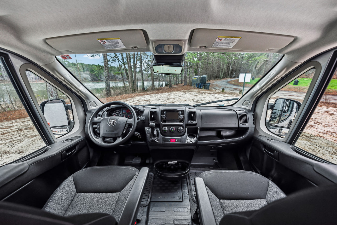 ready for adventure.|RV rental interior with a view of a tranquil lake and sandy beach from the open rear doors