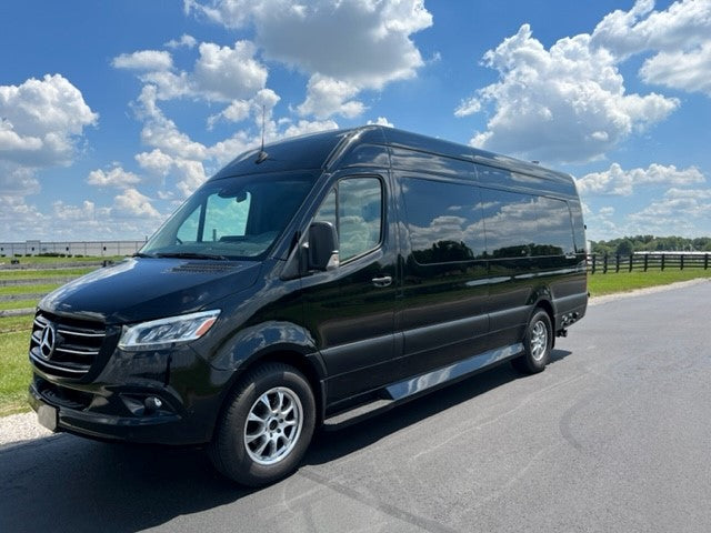 Black Mercedes-Benz Sprinter RV rental van. This versatile luxury vehicle is parked on asphalt under a bright blue sky.