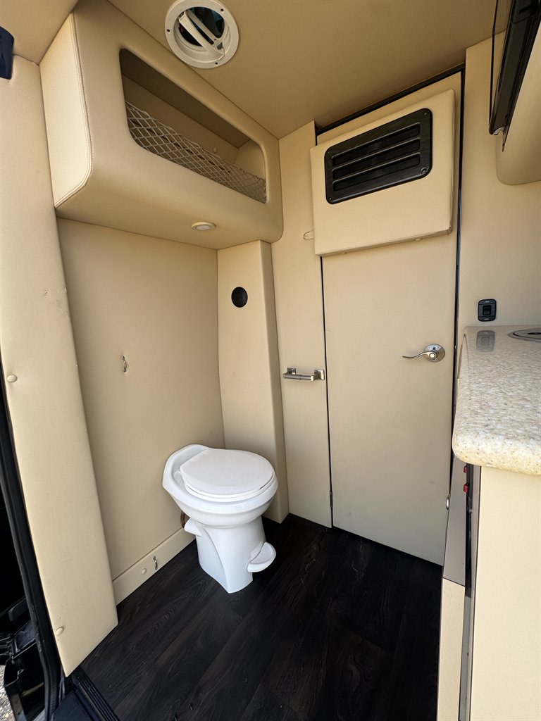 and dark wood flooring for ultimate comfort.|Premium rv rental interior: cream quilted leather captain's chairs
