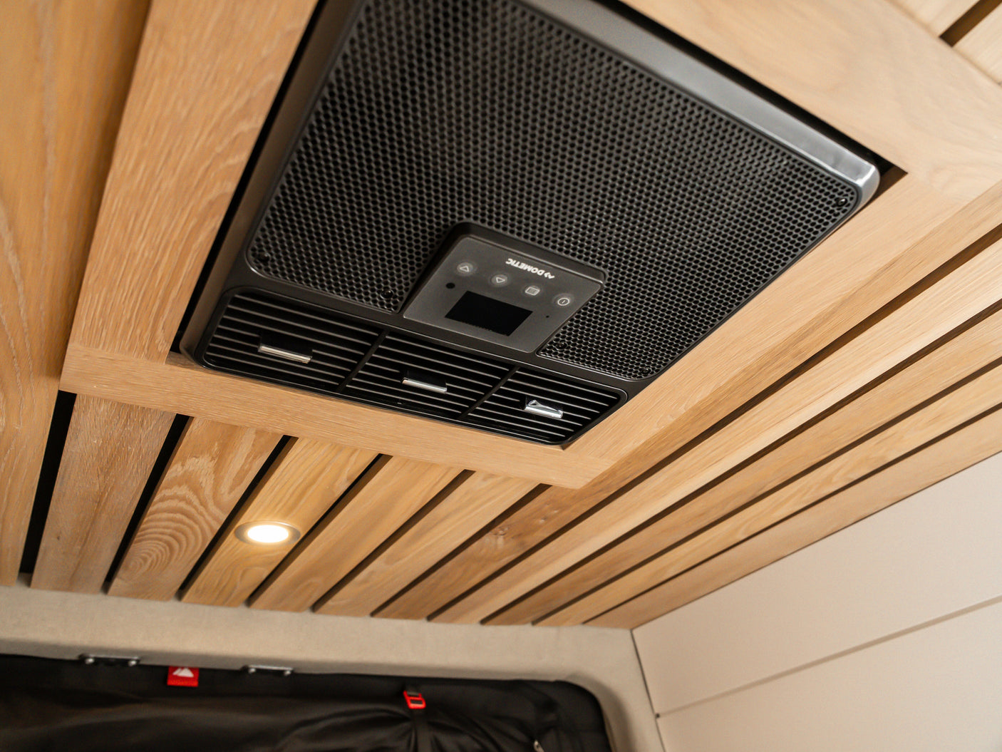 Modern RV rental interior: A Dometic AC unit is integrated into a stylish wooden slatted ceiling, featuring a spotlight.