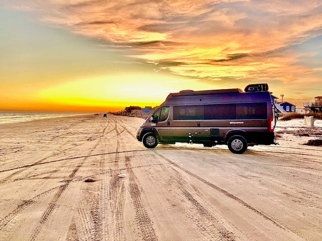 Thor Sequence RV rental on a sandy beach at sunset. Golden skies