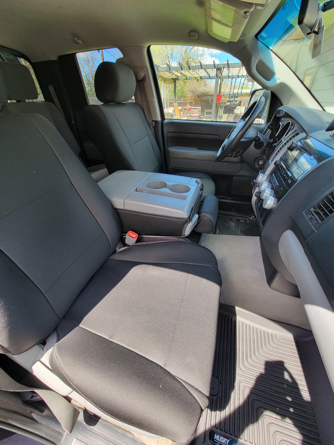 Interior view of an RV rental's front cabin: dark seats, gray center console with cup holders, and dashboard.