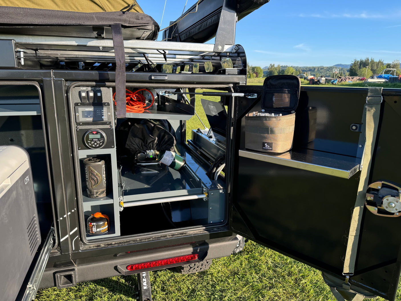 An RV rental's compact overland setup. Organized rear storage with Jetboil, power, and camp gear visible.