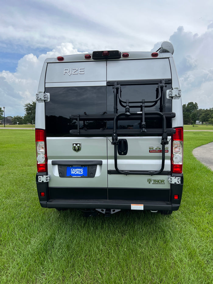 Rear view of a silver Thor Rize camper van, ideal for rv rental. Features include a Thule bike rack and Camping World license plate.