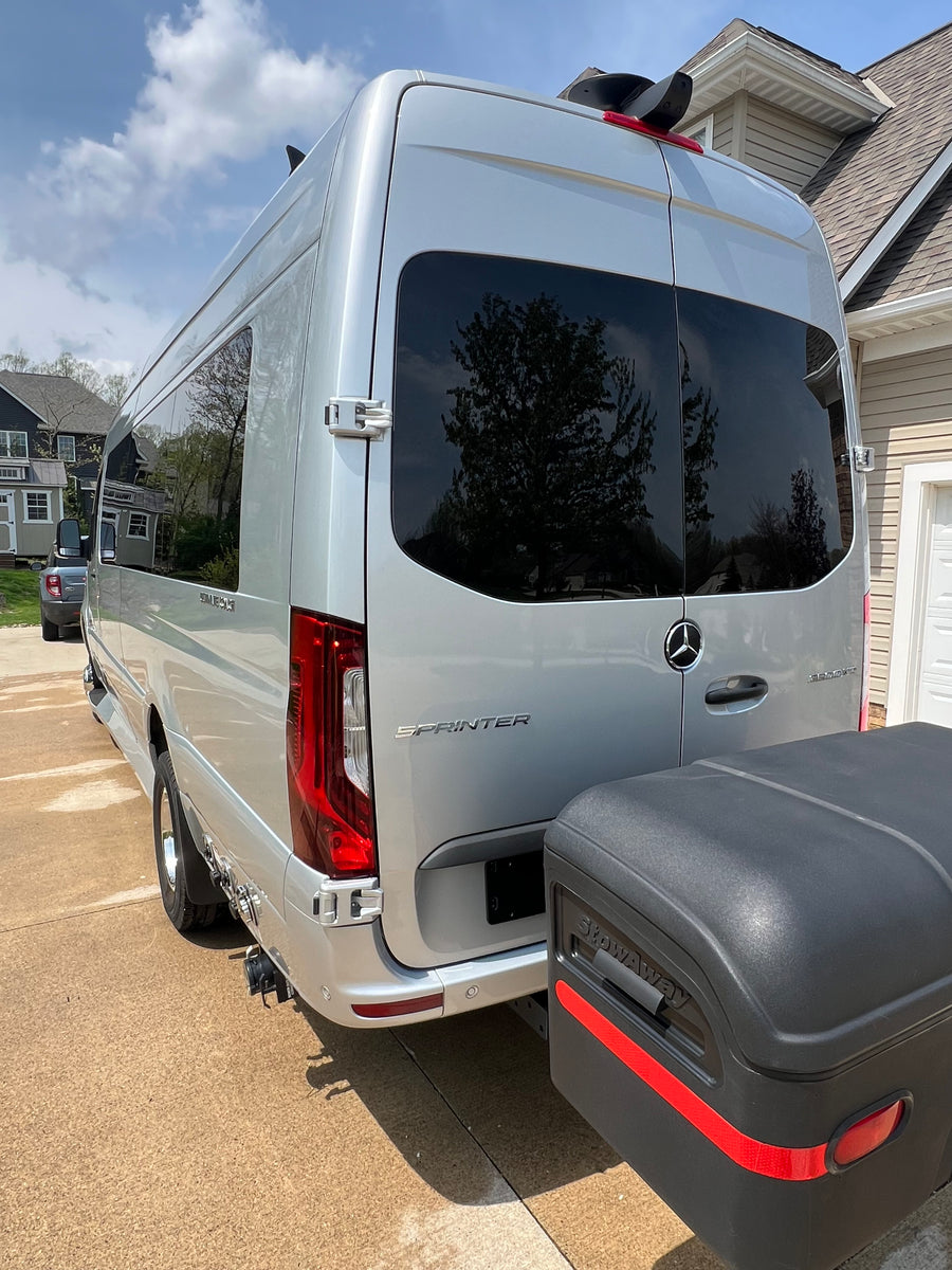 A sleek silver Mercedes-Benz Sprinter van, an ideal RV rental, is parked outdoors with a rear-mounted StowAway cargo box.