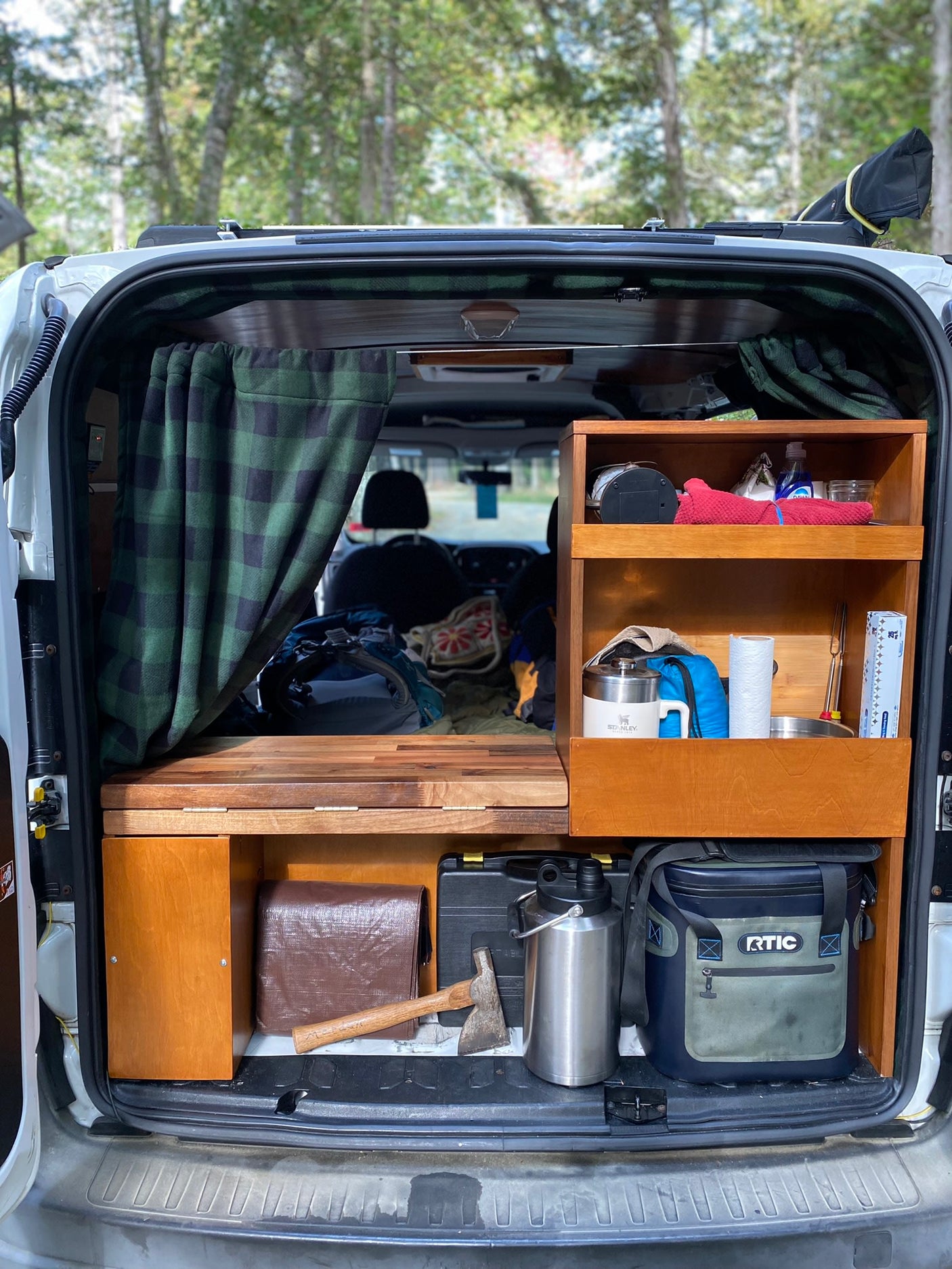 and a peaceful forest view through the large window.|Compact rv rental interior featuring a wood ceiling