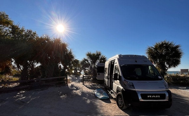 sun shining. A paddleboard is next to the van