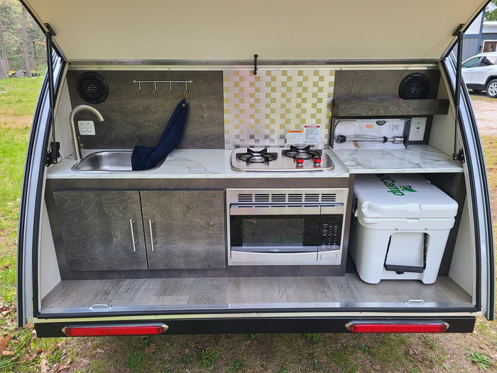 ready for outdoor camping adventures. Features durable off-road tires.|RV rental: rear hatch reveals a compact outdoor kitchen with sink