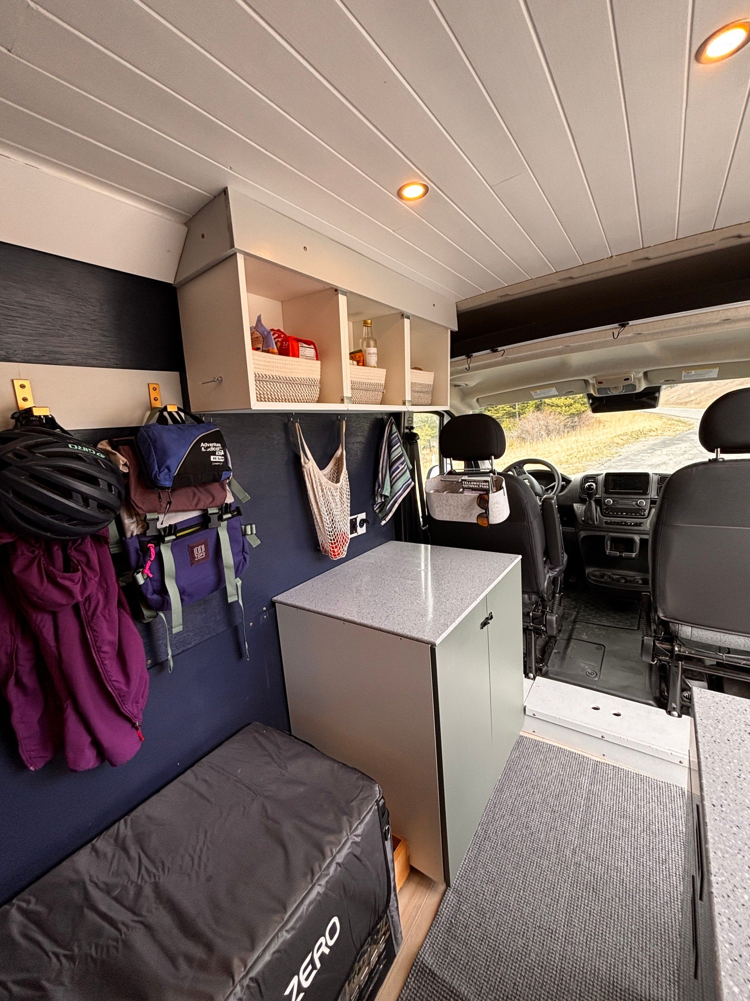 Van conversion RV rental: functional interior with storage, kitchenette, and driver's area, ready for road trips.