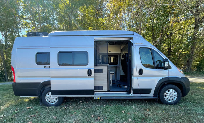 Get ready for adventure! This silver RV rental camper van with open side door shows off its cozy interior.