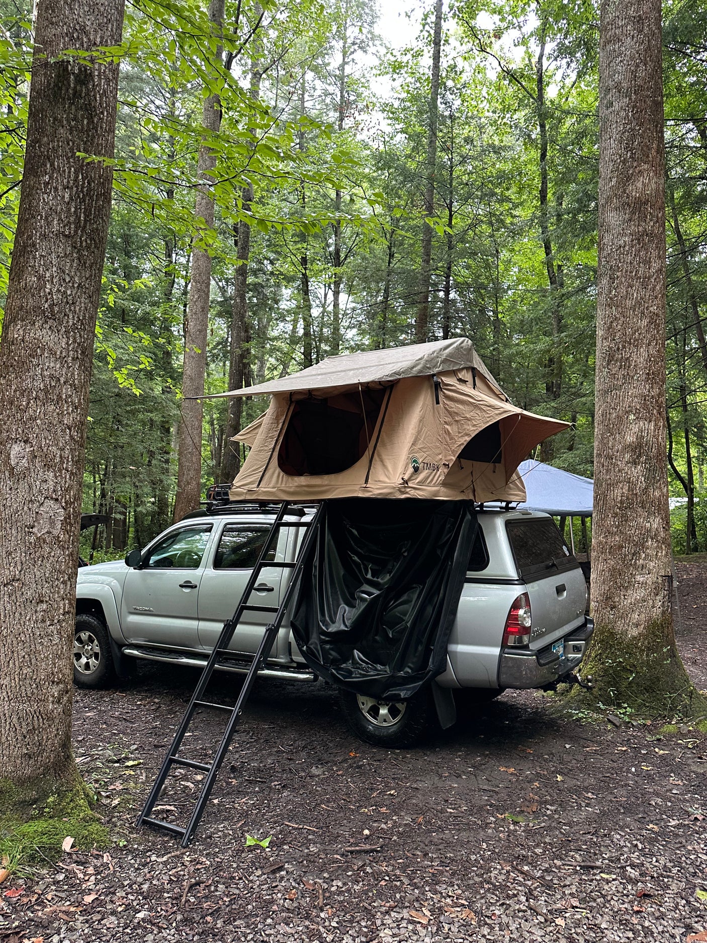 offering an RV rental alternative.|Silver Toyota Tacoma with rooftop tent by Great Smoky Mountains National Park sign. An ideal rv rental alternative for adventure!|Silver truck with a rooftop tent set up for camping in a lush forest. A great overlanding alternative to an RV rental!