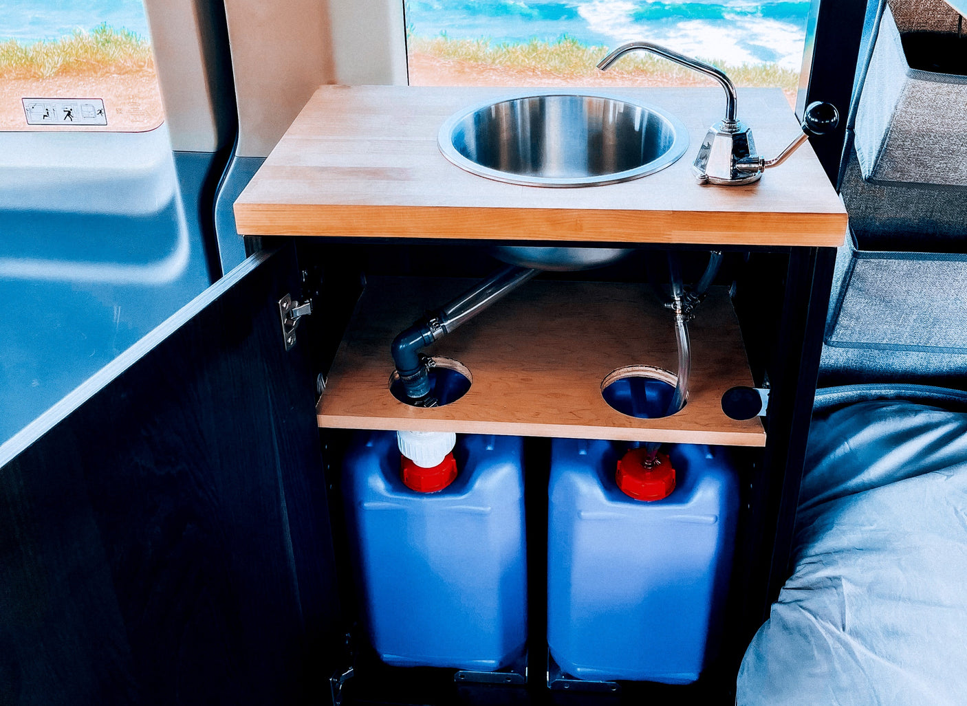 This RV rental features a compact kitchenette with a sink & water tanks, perfect for camper van adventures.