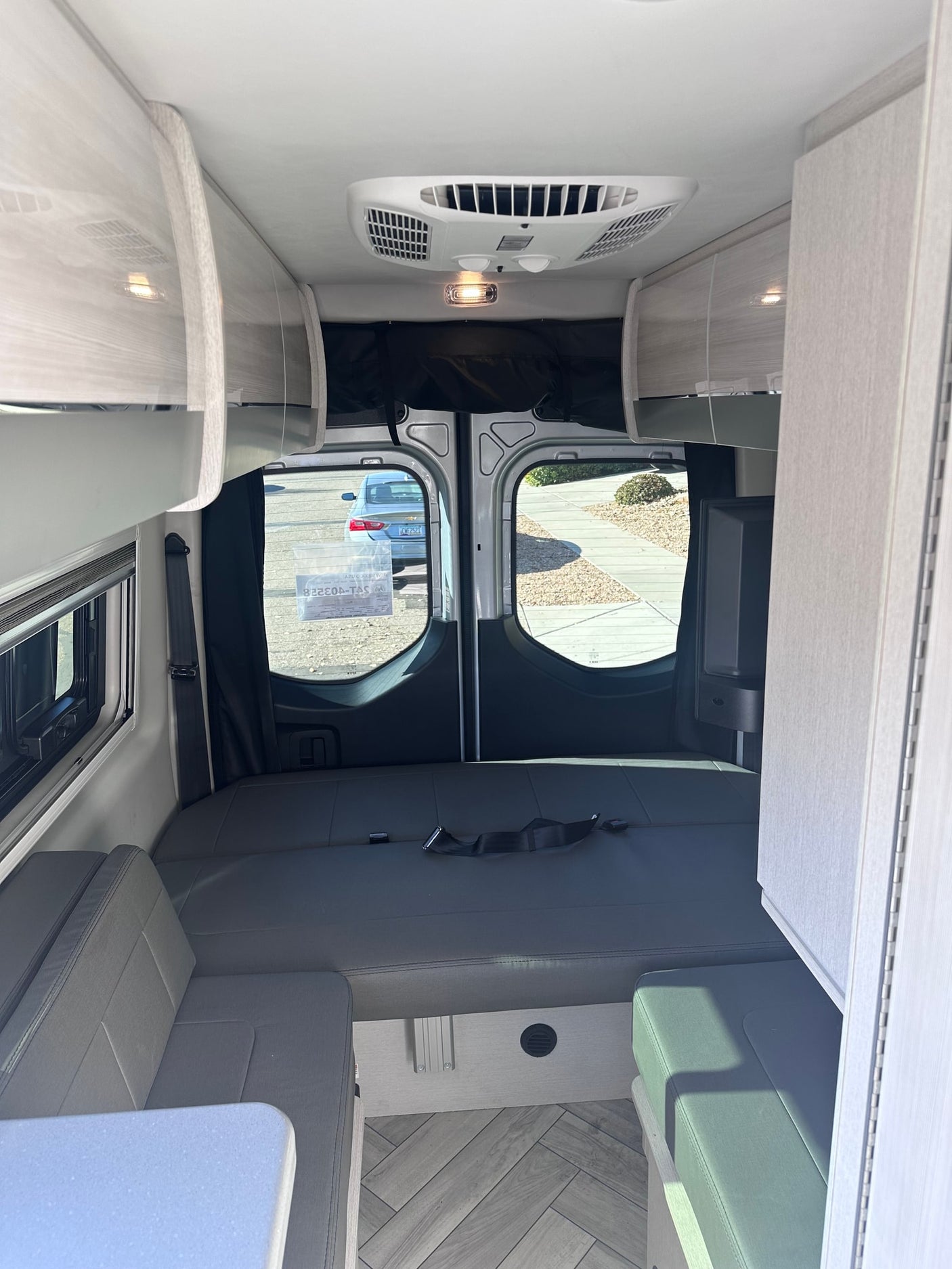 and fire extinguisher for safety.|Inside an **RV rental**: rear cargo area with a modular storage system and tie-down straps for secure storage.|Inside an RV rental: bright galley with a chrome faucet