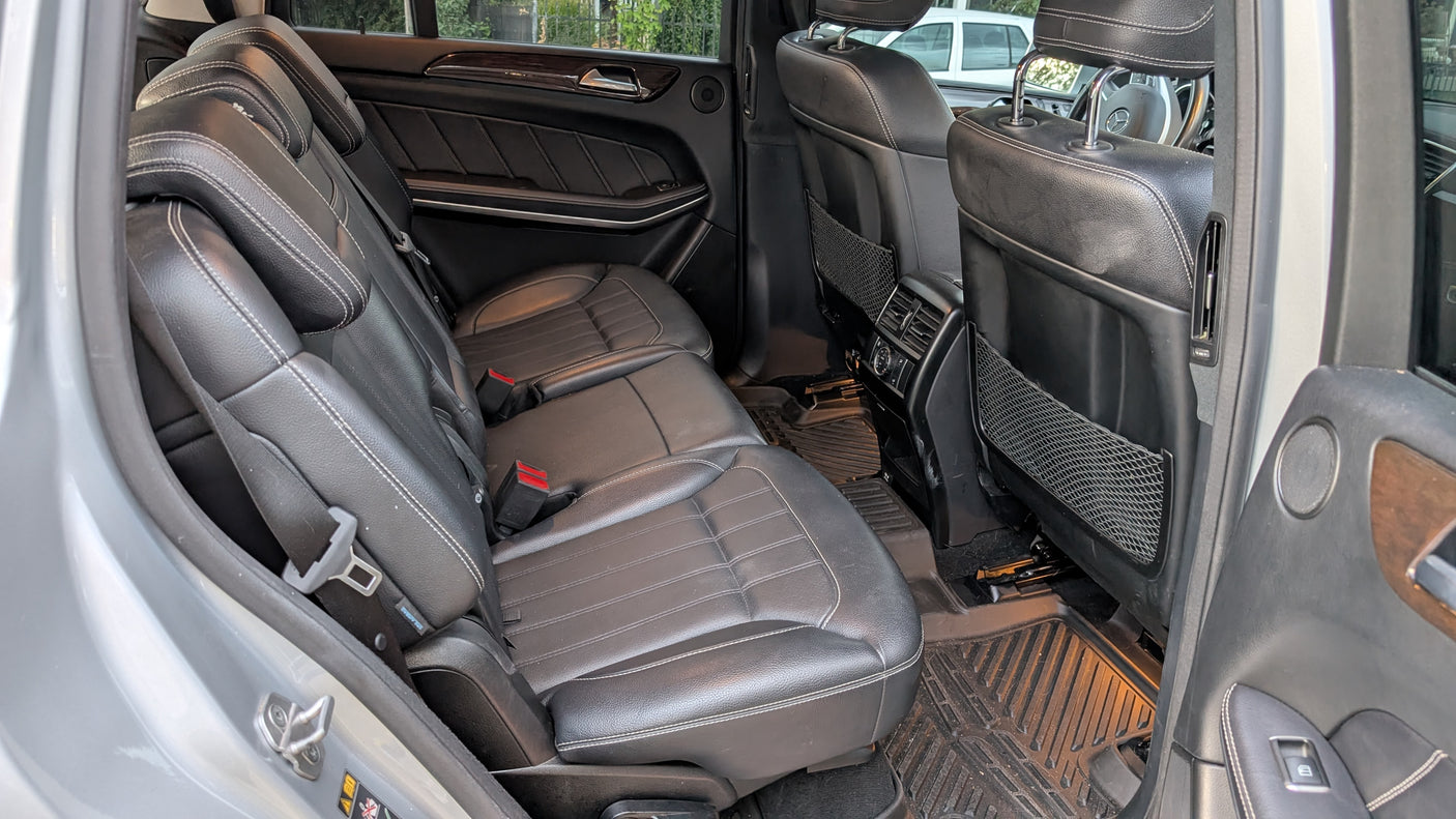 Roomy vehicle interior for your RV rental journey, showing black leather rear seats with white stitching and durable floor mats.