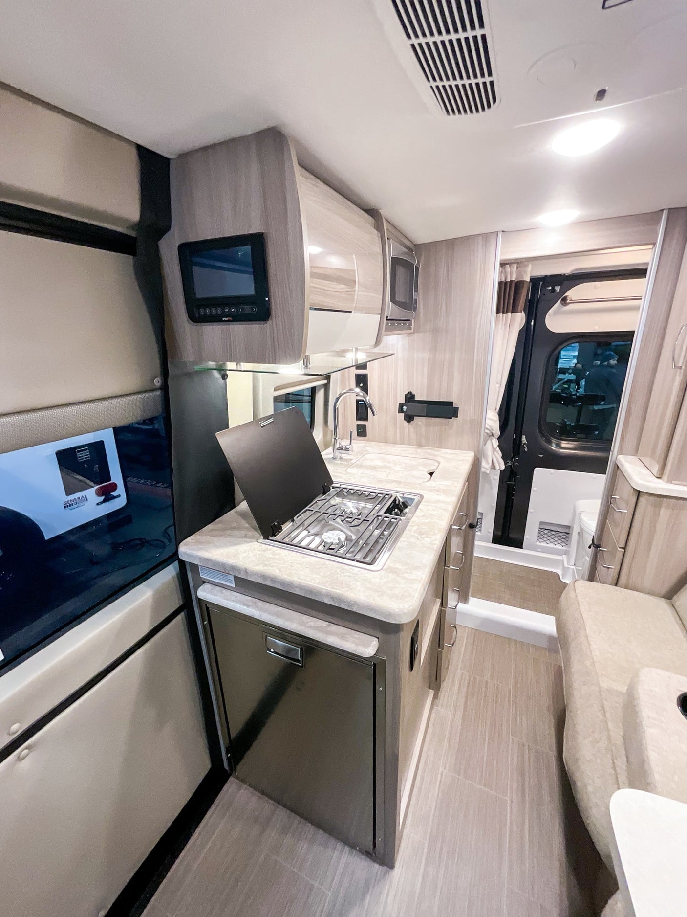 Explore this modern RV rental interior: a compact kitchen, cozy living area, and amenities perfect for your adventures.