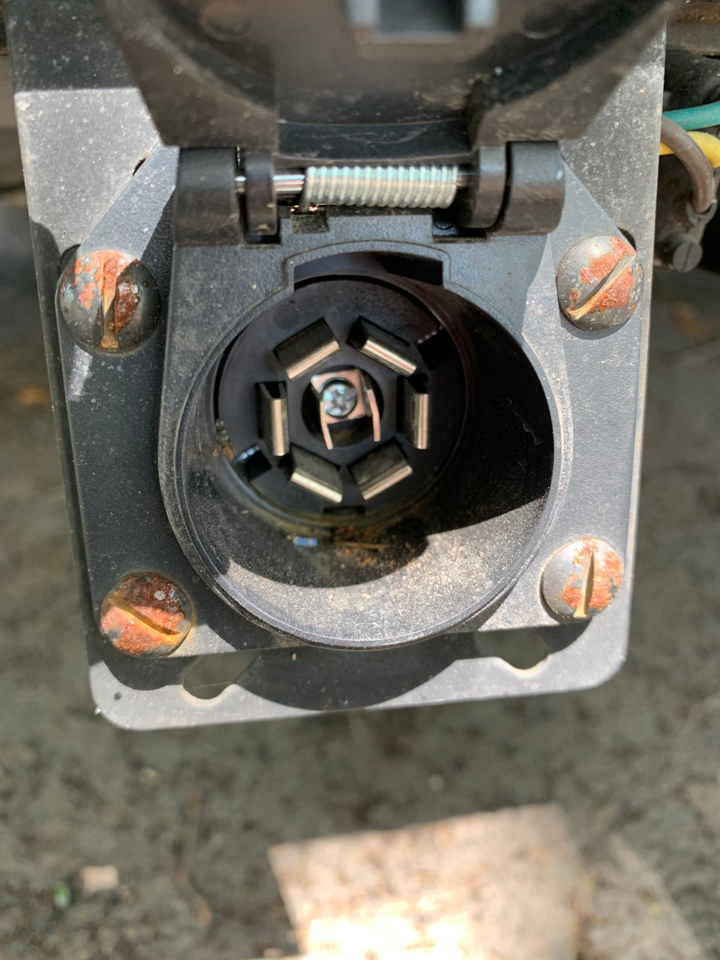 Close-up of a rusty 7-pin trailer connector on a vehicle, essential for rv rental towing.