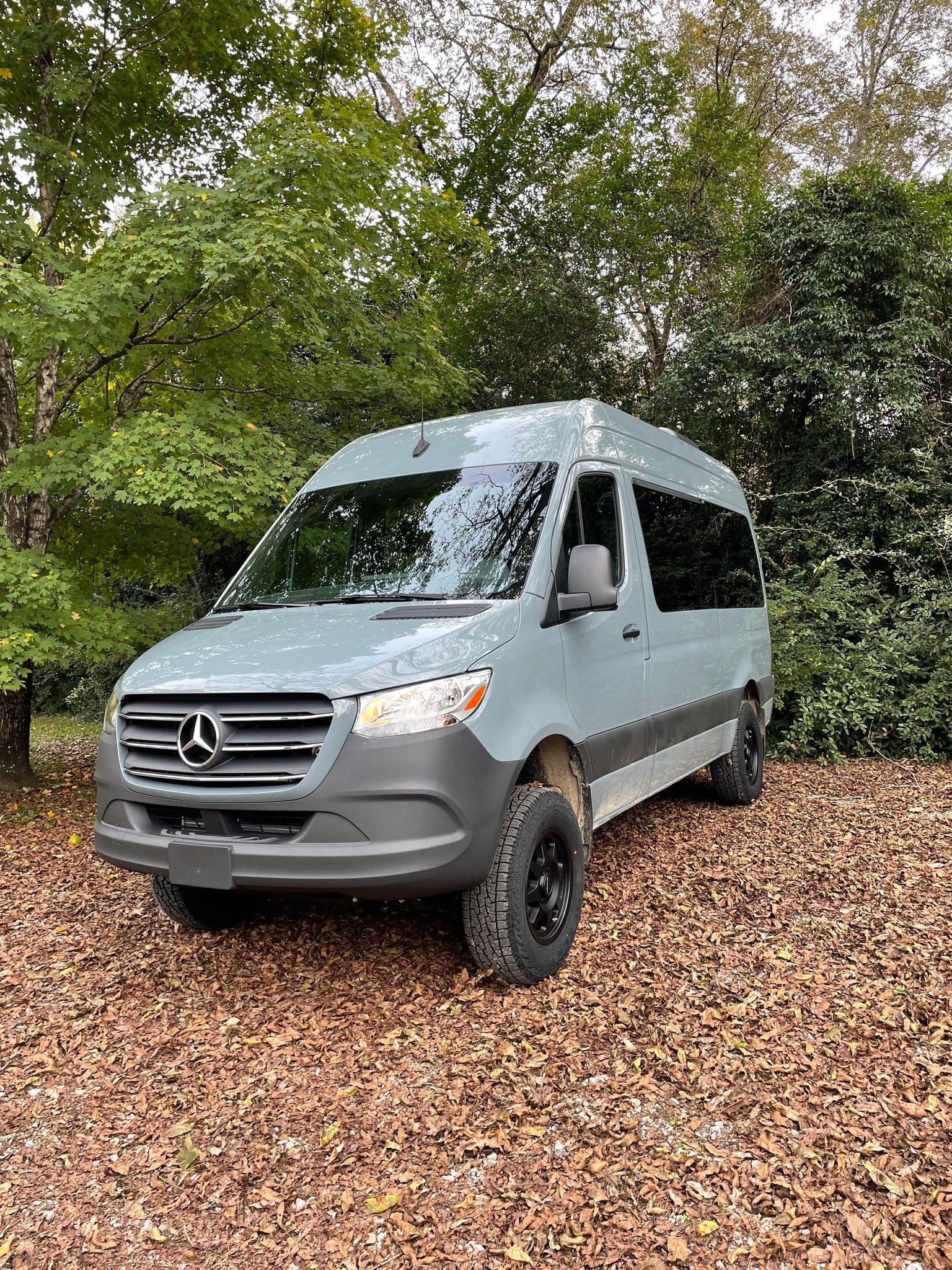 this modern passenger van features multiple rows of dark seats for comfortable group transport.|A light grey Mercedes-Benz Sprinter van