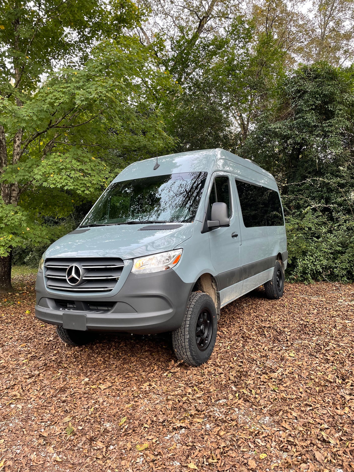 this modern passenger van features multiple rows of dark seats for comfortable group transport.|A light grey Mercedes-Benz Sprinter van