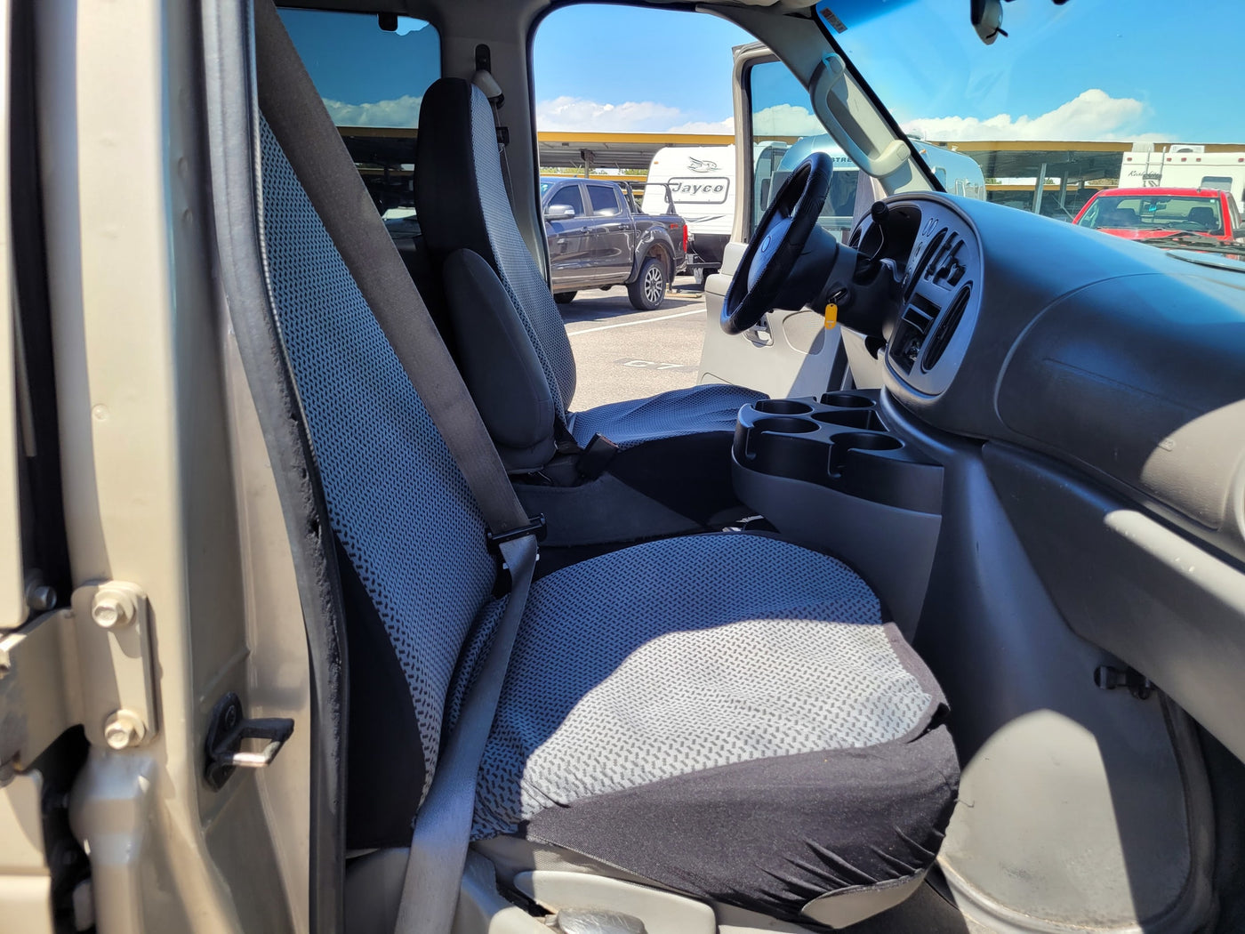 Interior of an RV rental van: driver's and passenger seats, dashboard, and a lot of parked RVs outside. — photo 12