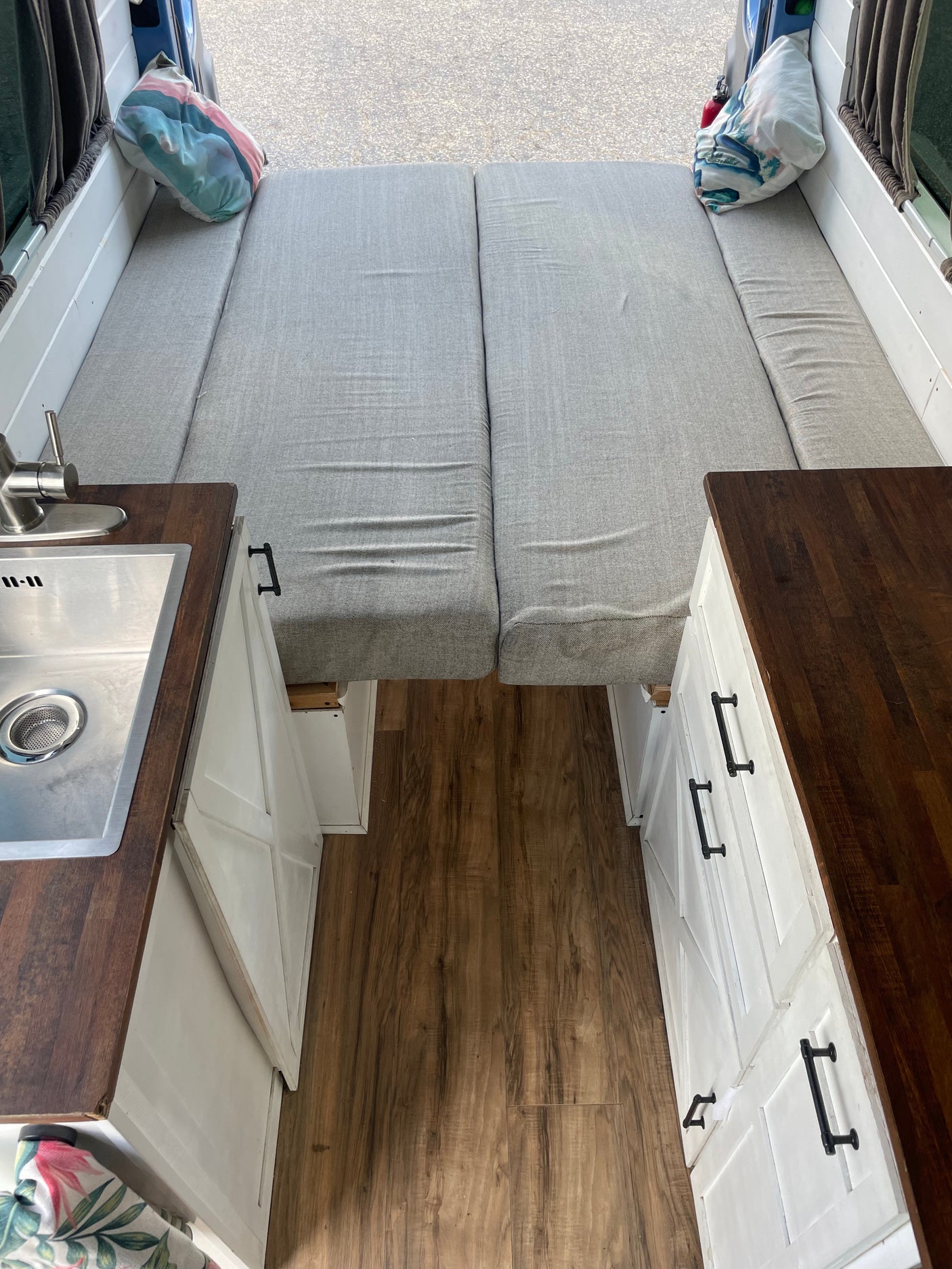 Cozy RV rental interior with convertible bed, custom kitchen with sink, and storage cabinets, ready for adventure.