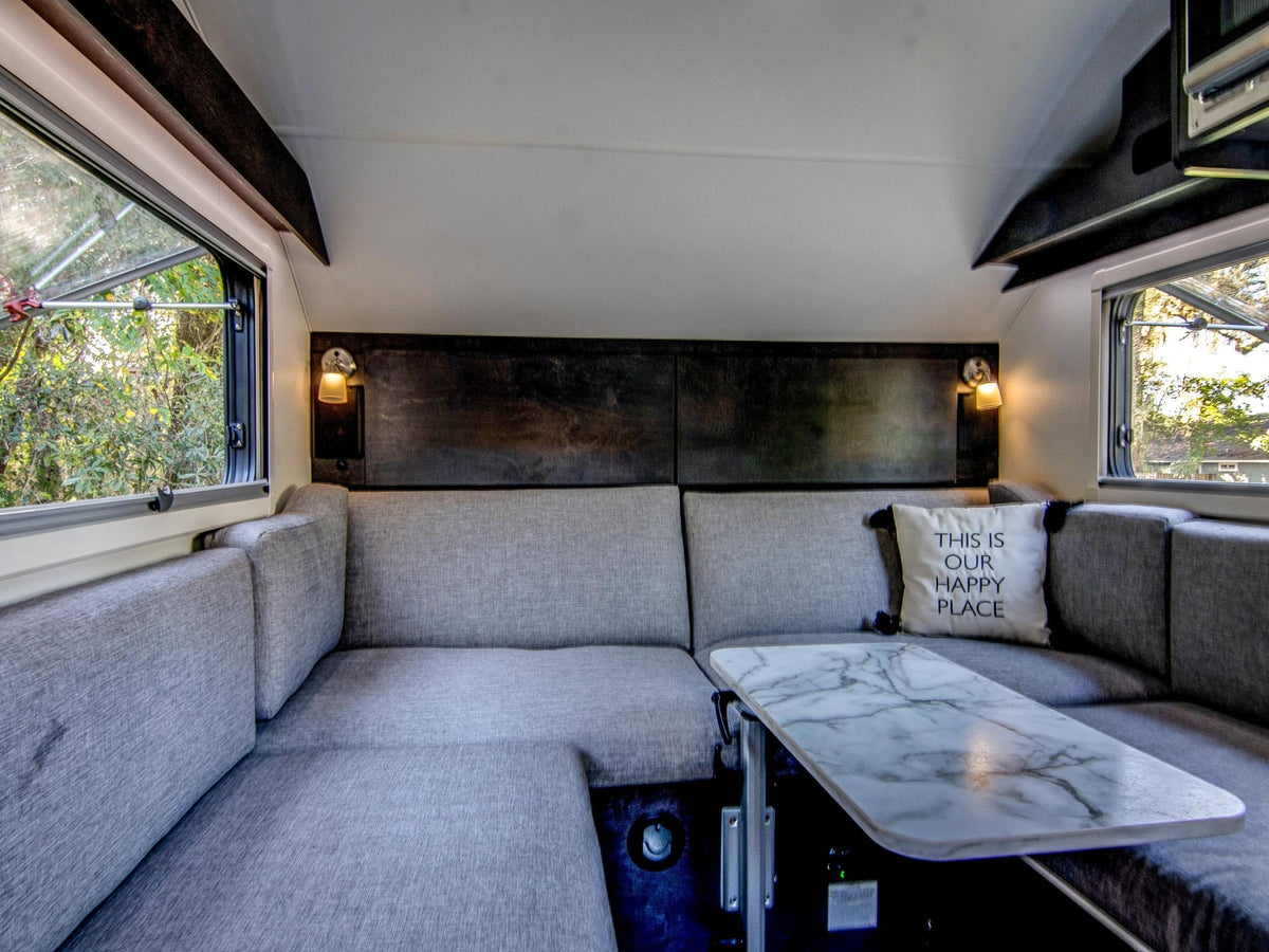 parked on grass. Ideal for camping; features a spare tire & storage box.|Inside an rv rental: compact kitchen with microwave — photo 10
