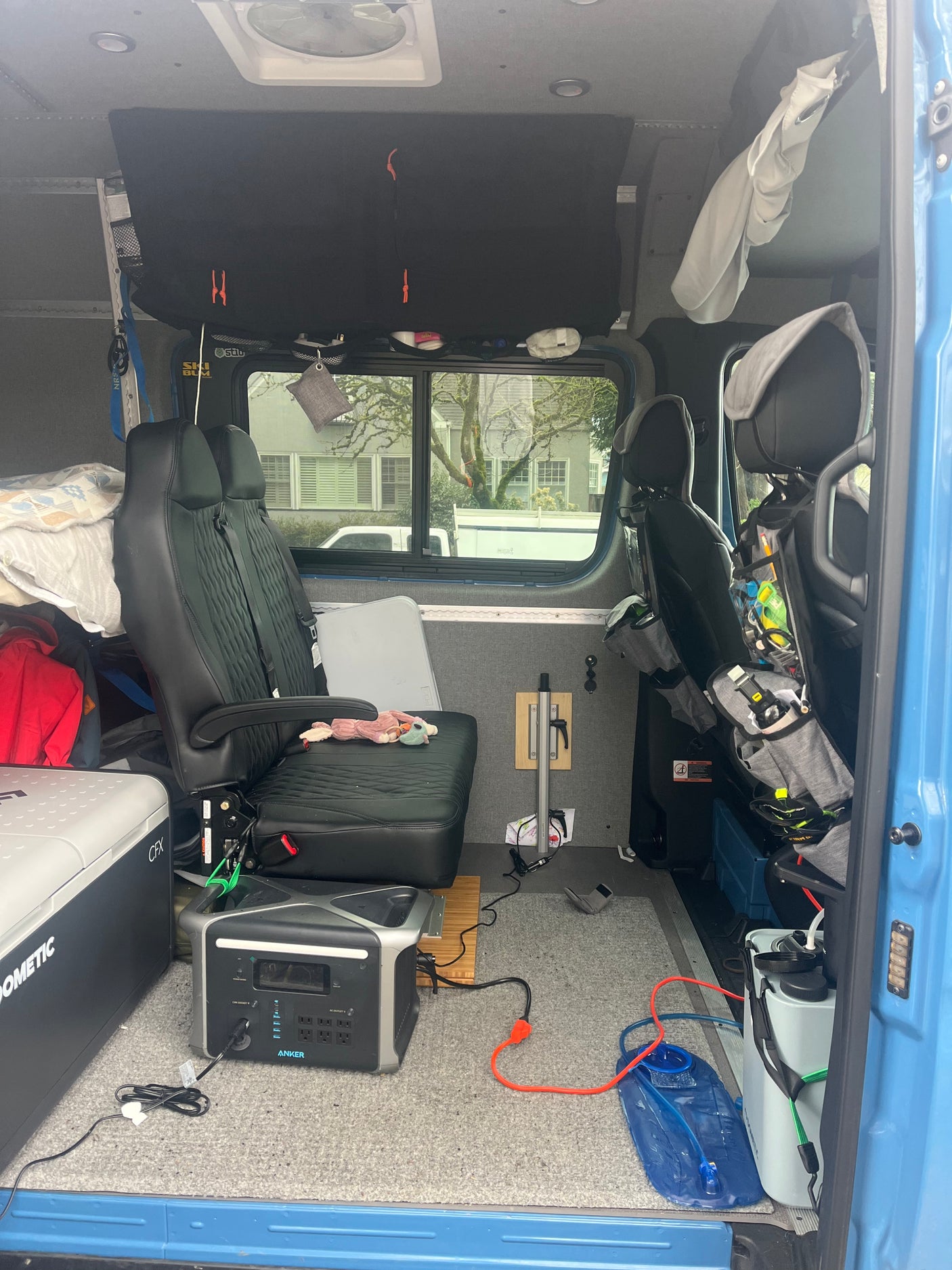 This RV rental showcases a functional camper van interior with flexible seating, portable power, cooler, and water storage solutions.
