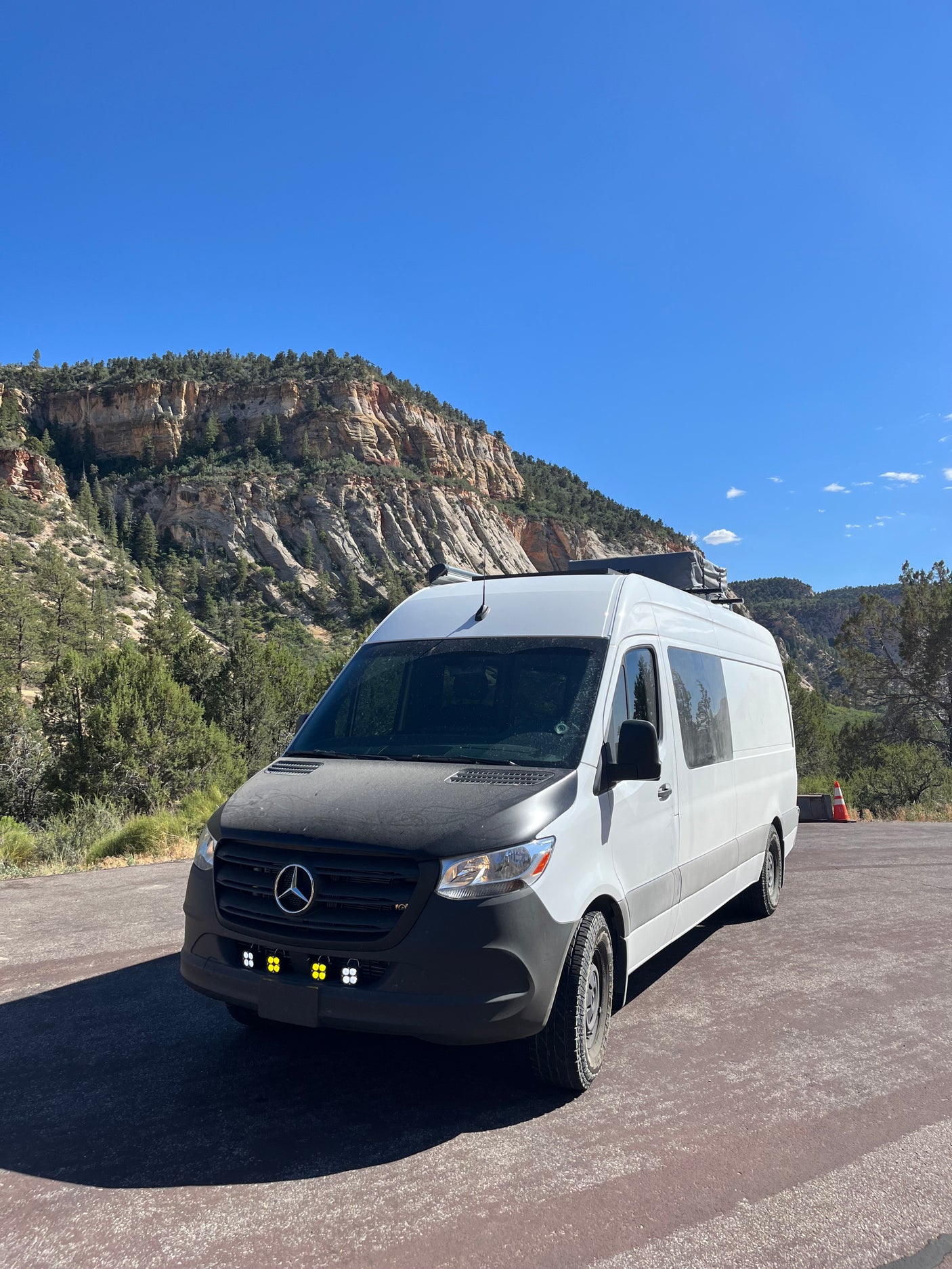 White Sprinter van for RV rental parked against scenic mountains. Ready for van life adventures in the outdoors.