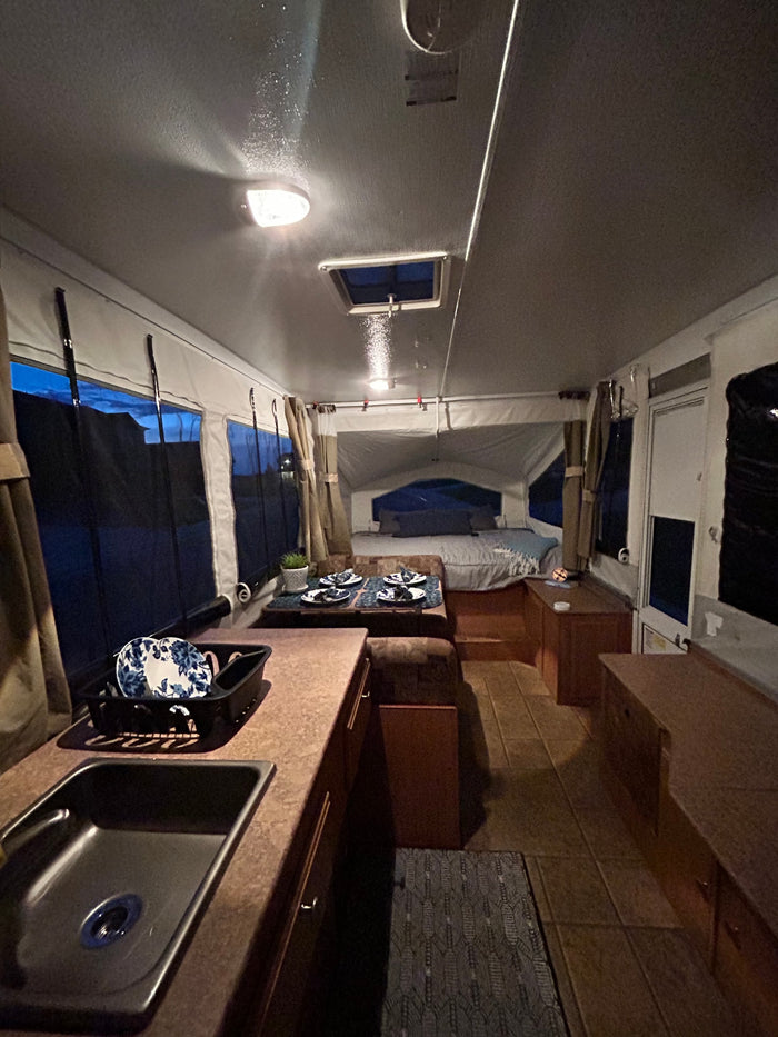 Cozy RV rental interior at dusk. Features include a kitchen sink, dining area, and comfortable bed.