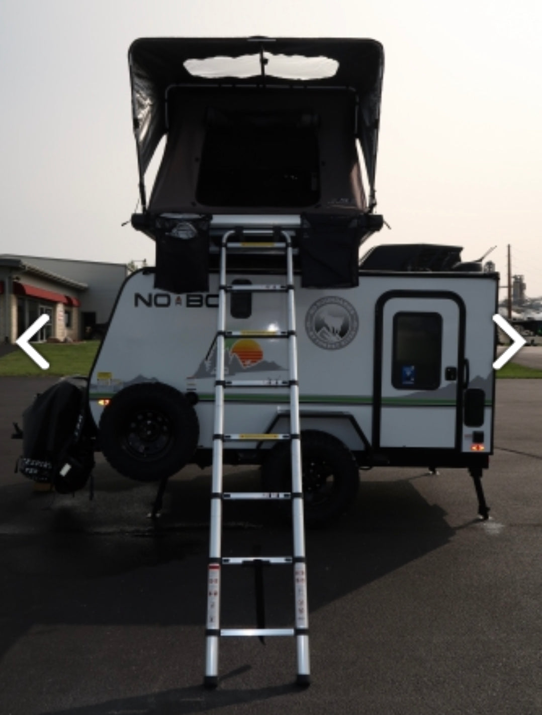Compact travel trailer RV rental with open rooftop tent & ladder, ready for your next outdoor adventure.