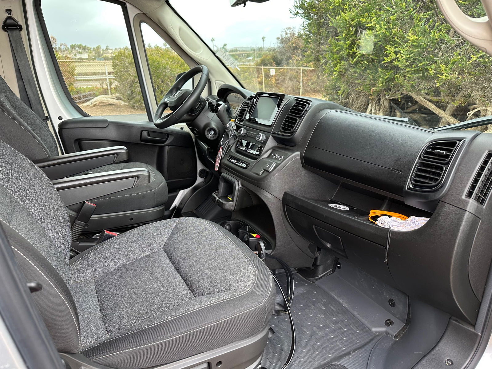 Inside an RV rental van's front cabin, showing the dashboard, steering wheel, and seats with a view out the windows.