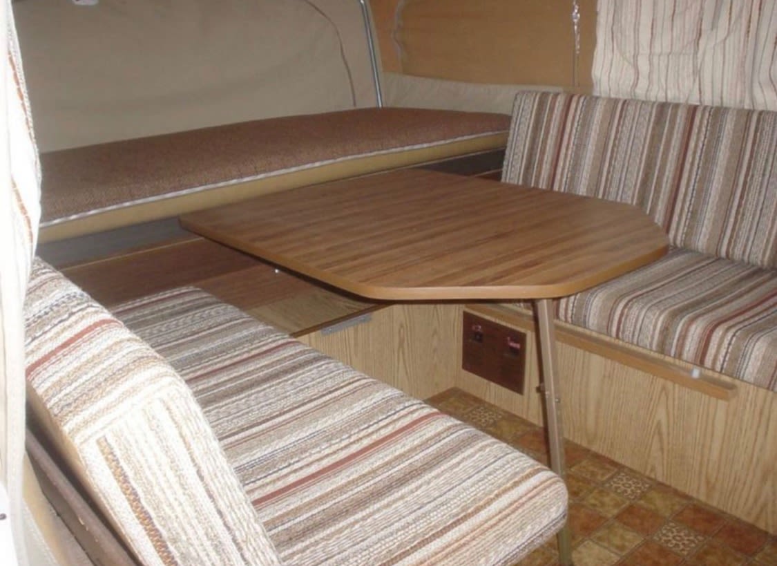 is available for RV rental. Ideal for camping adventures.|RV rental interior: a compact dinette with striped benches