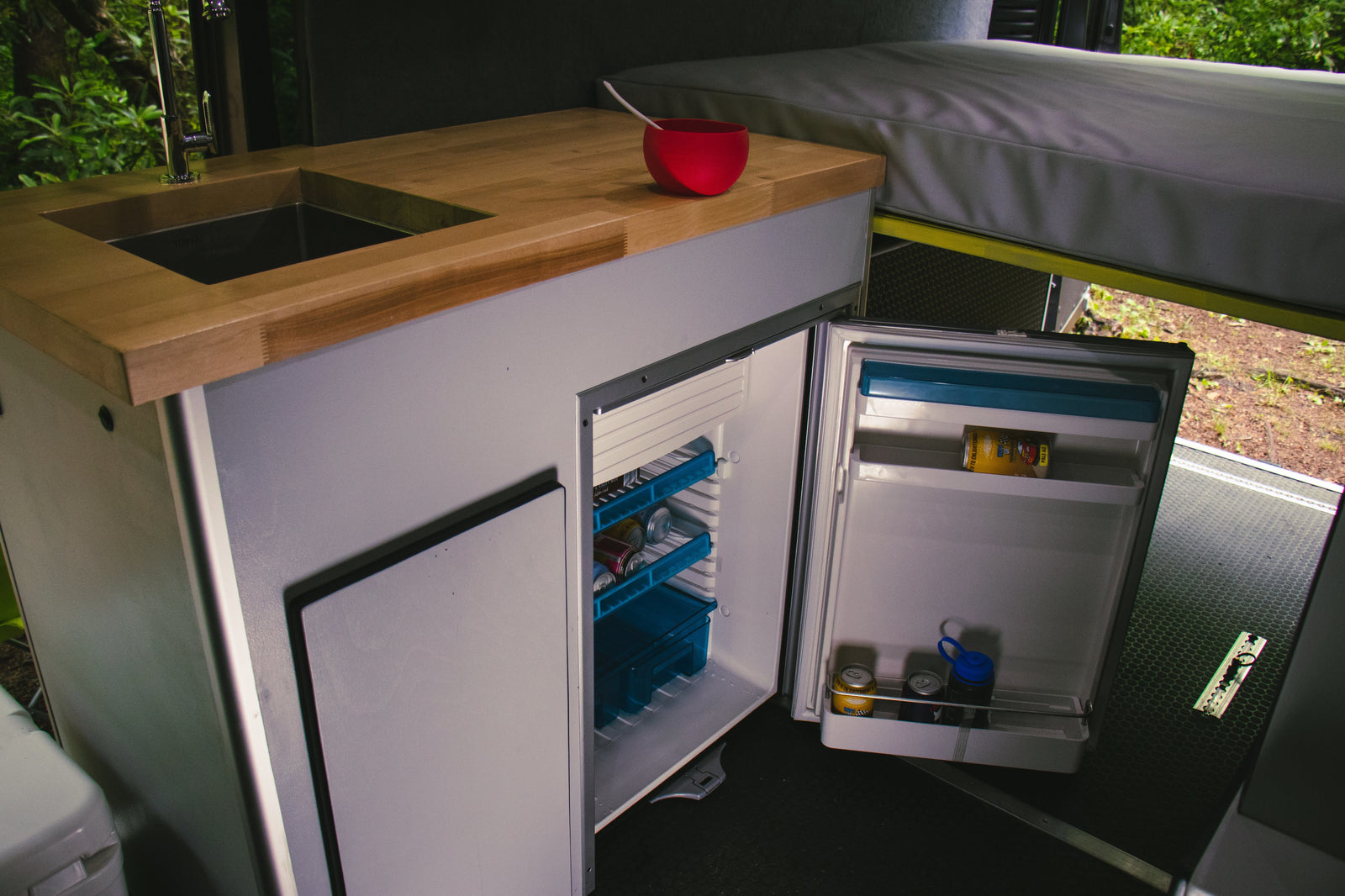 Step into this RV rental's practical kitchen area, complete with a sink, wood counter, and a fully accessible fridge.