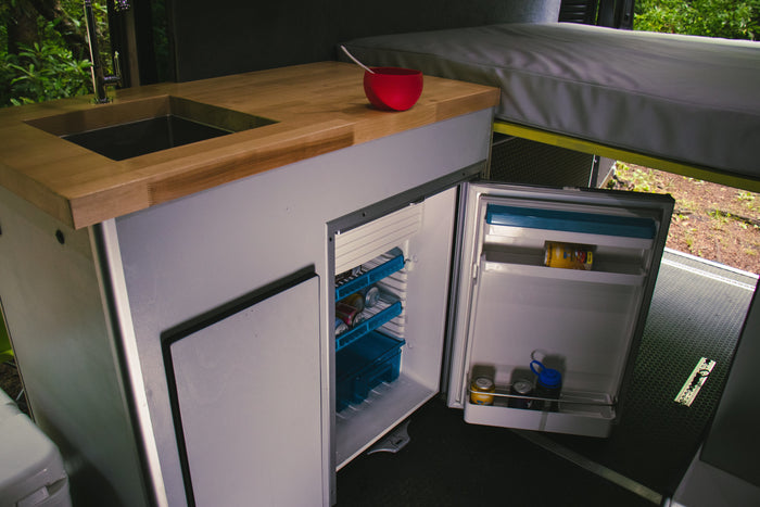 Step into this RV rental's practical kitchen area, complete with a sink, wood counter, and a fully accessible fridge.