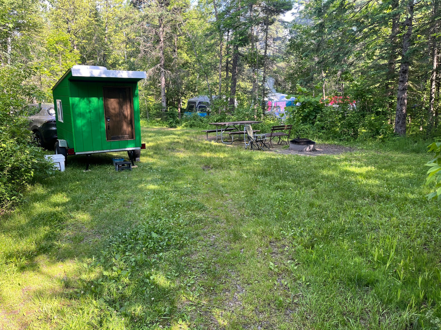 ready for your next adventure.|Gray SUV towing a bright green custom camper trailer on a driveway. Imagine this for an RV rental adventure!|Bright green custom mobile shelter on a trailer with a roof vent
