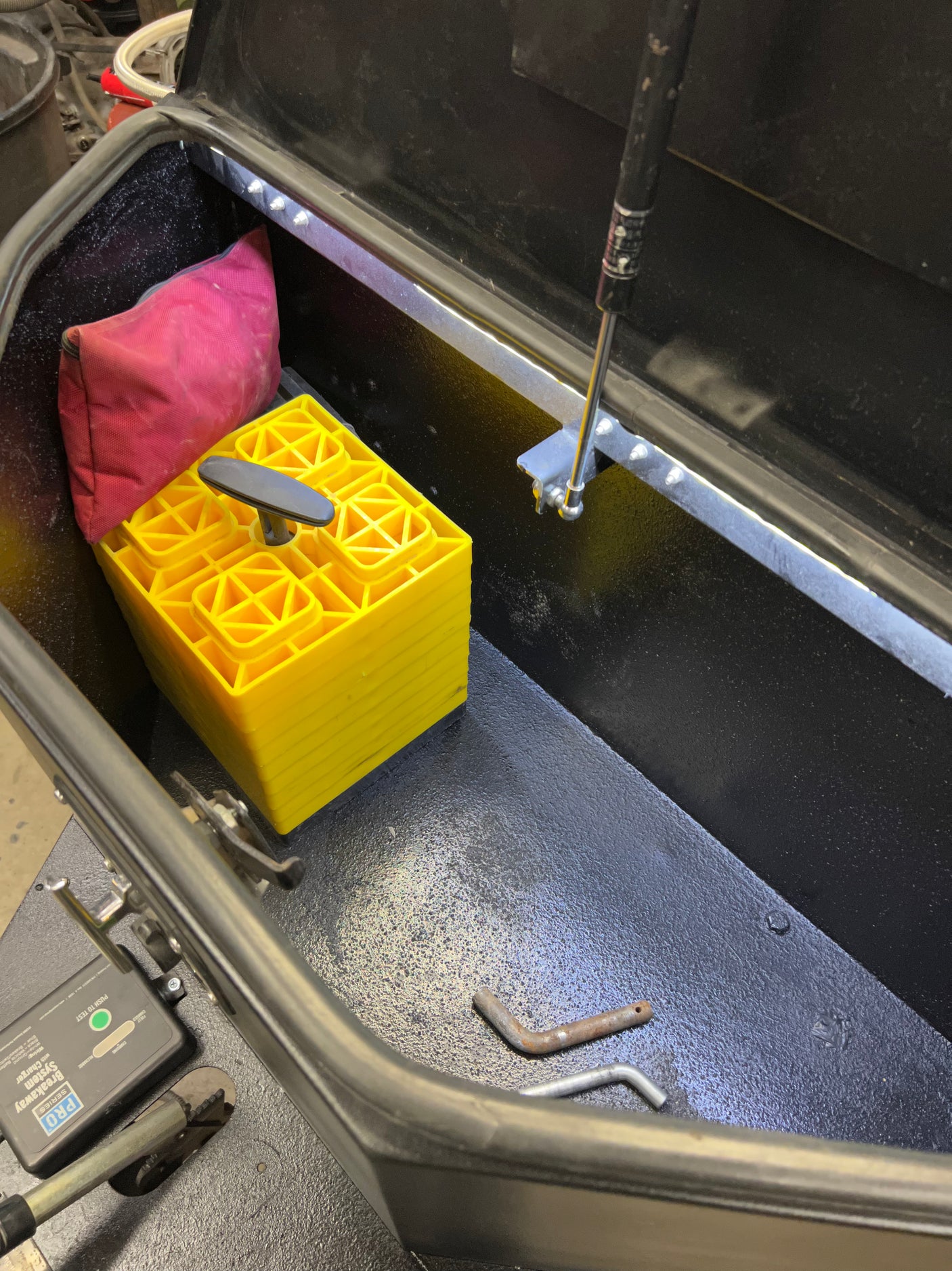 View inside an RV rental storage box containing yellow leveling blocks, a red bag, and a PRO Series Breakaway System.
