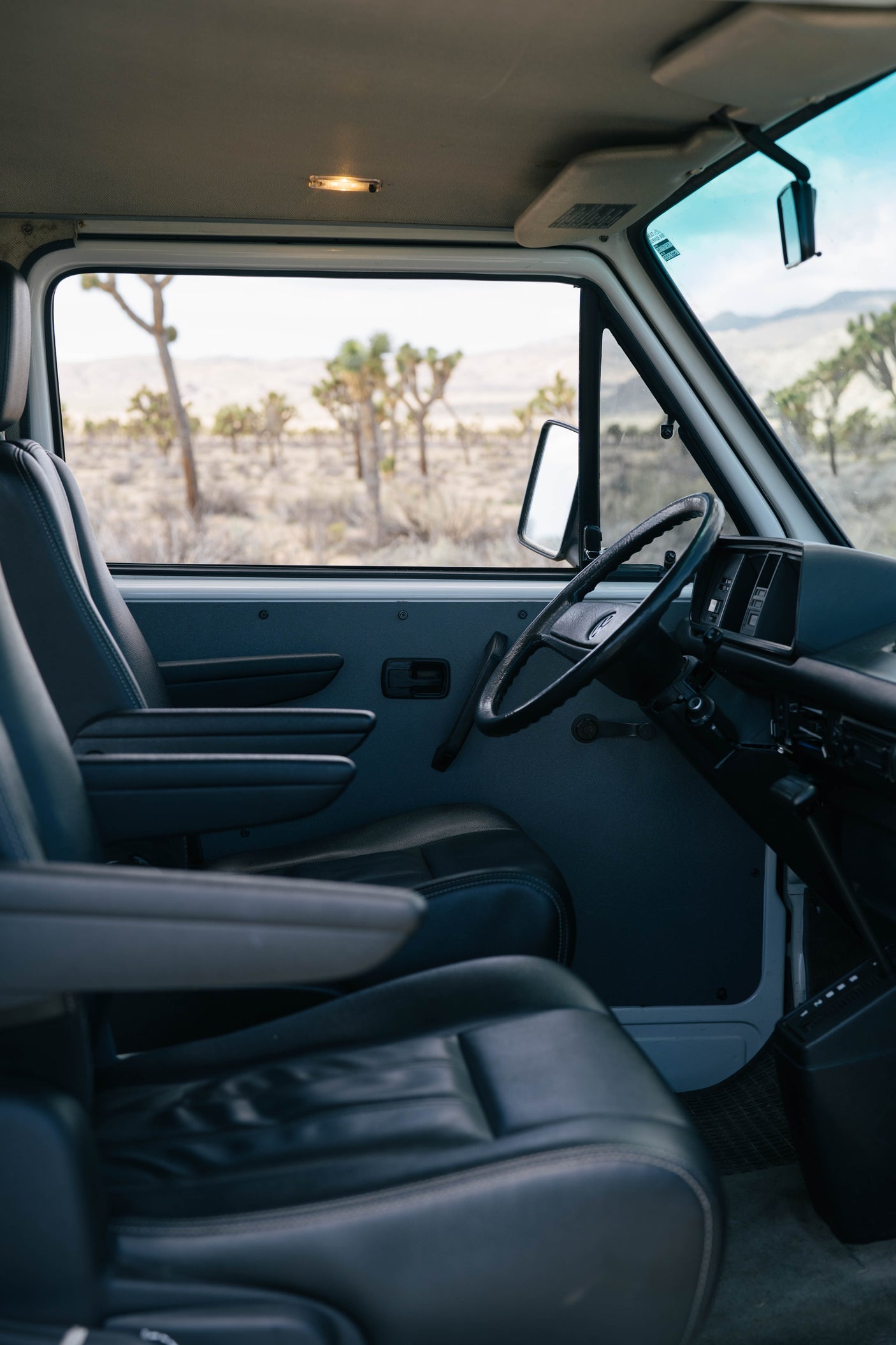 RV rental: comfy van interior with leather seats, a steering wheel, and a scenic desert view of Joshua trees.